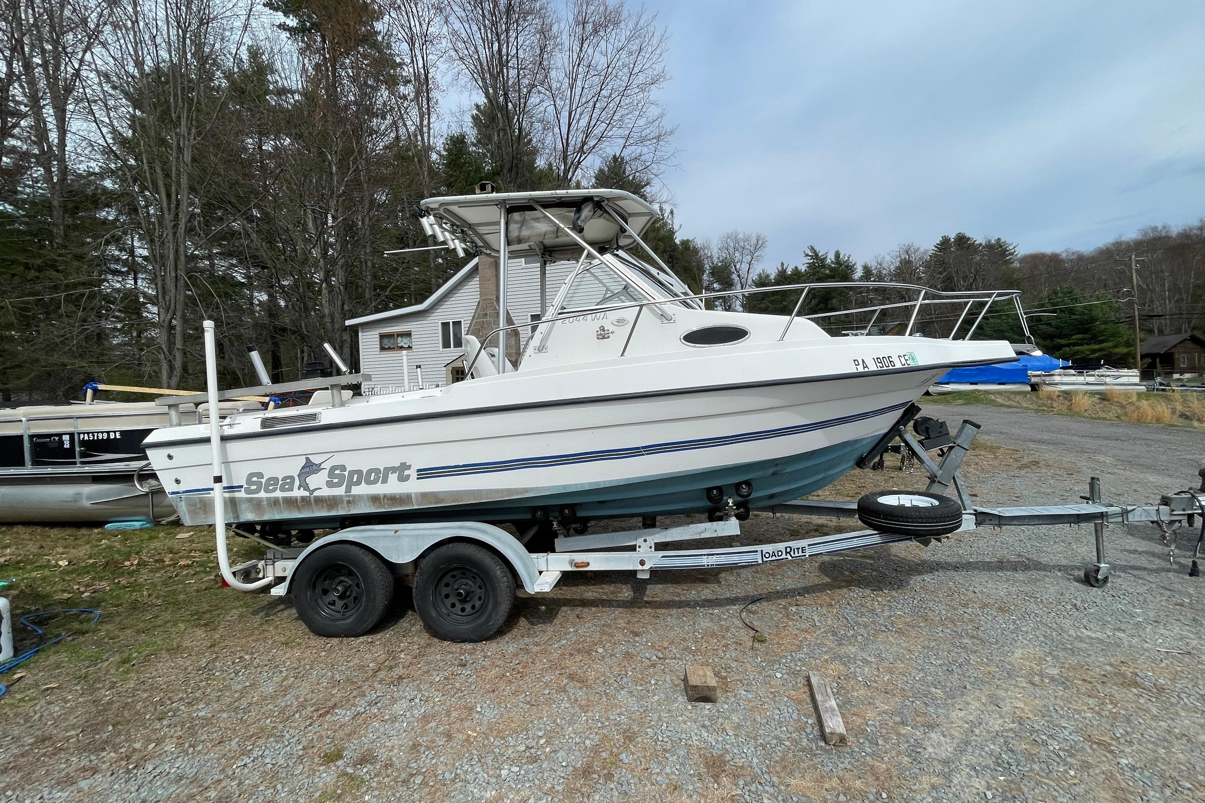 1999 Sea Sport 2044 Walk Around boat on trailer, parked outdoors near trees.