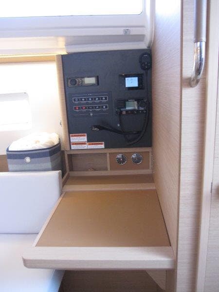 Navigation station of 2024 Jeanneau 380 sailboat with control panel and storage.