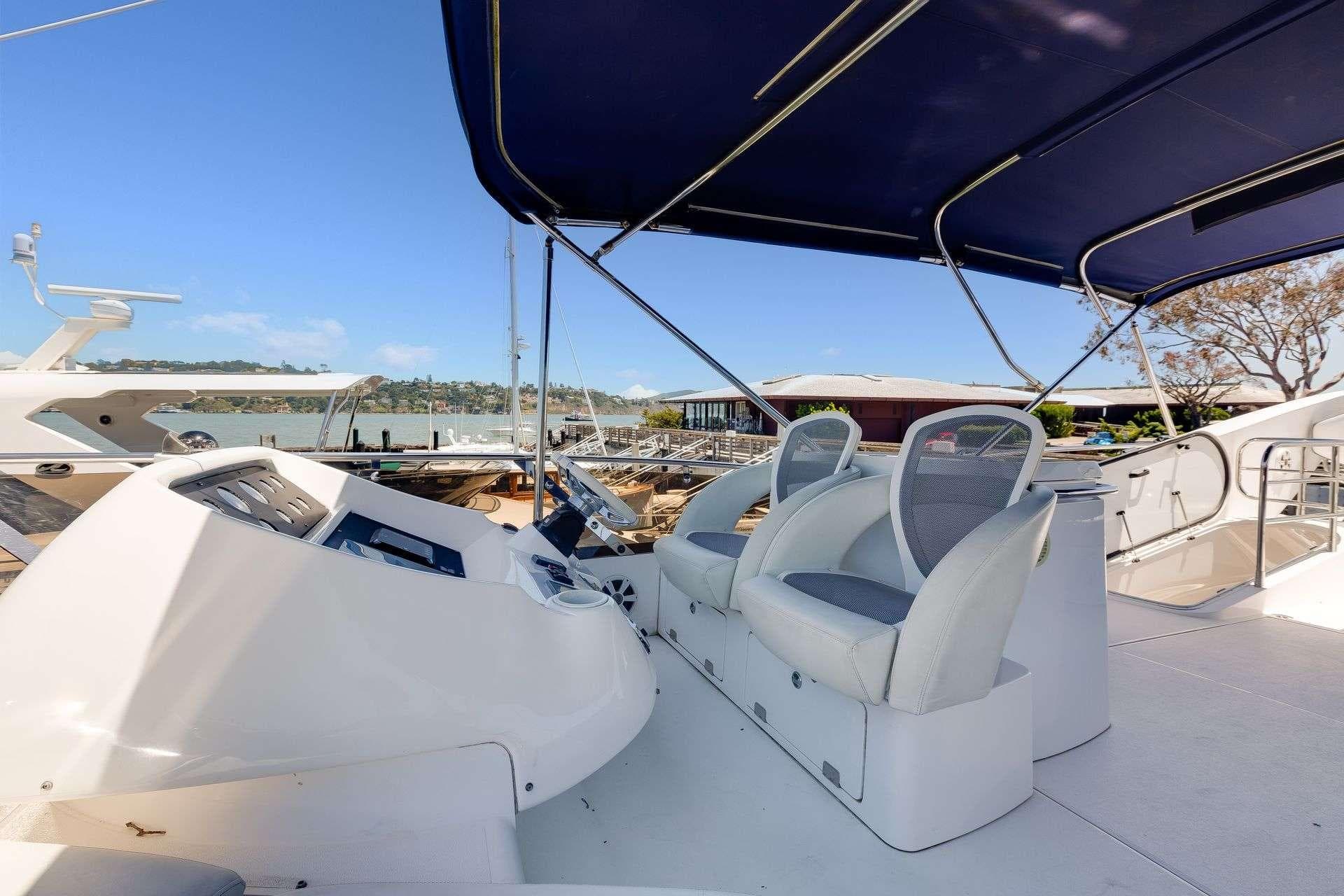 2009 Sunseeker Manhattan 70 yacht helm with seating and canopy, docked in marina.
