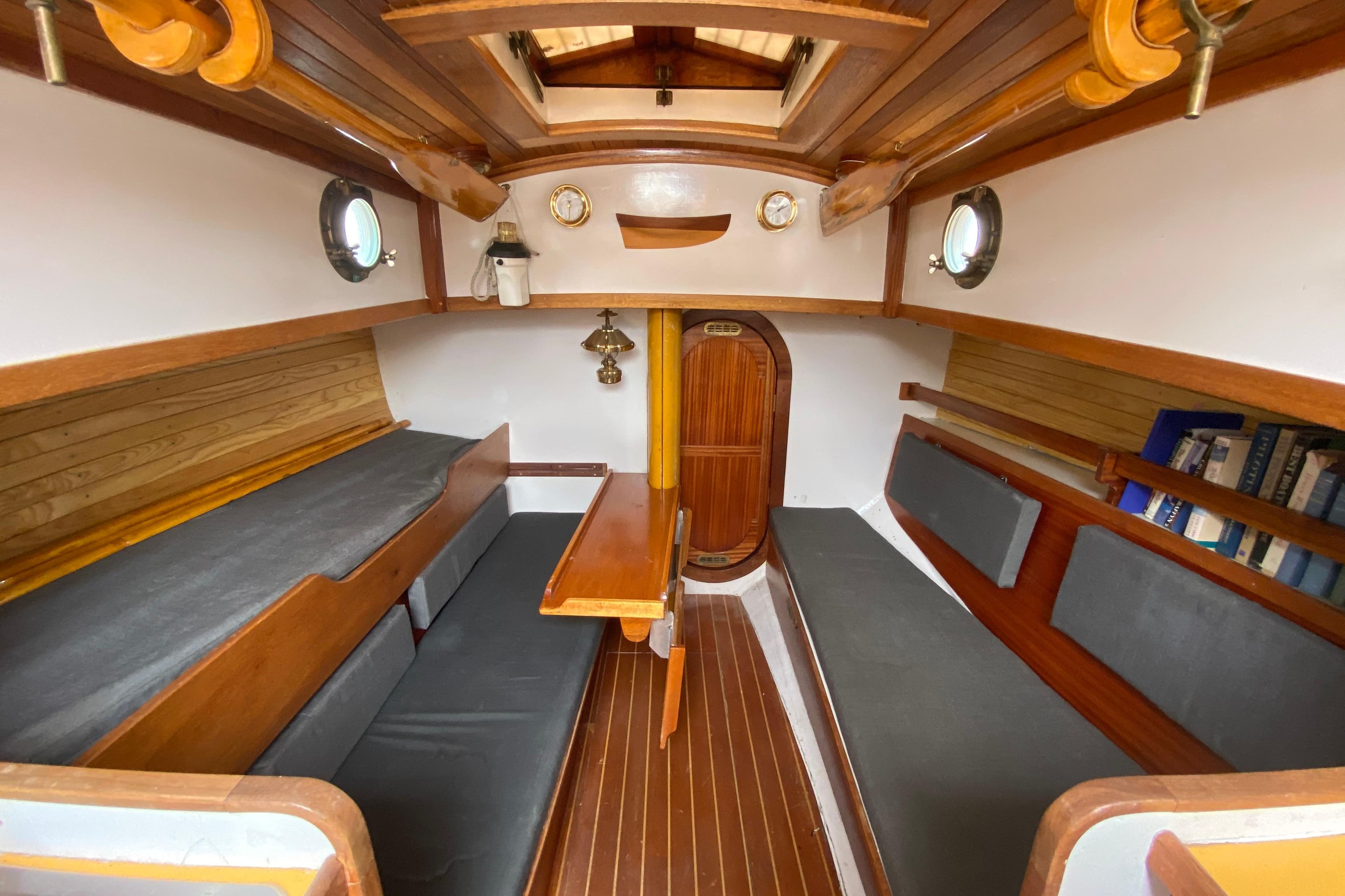 Interior of a 1978 Bristol Channel Cutter 28 sailboat, featuring wooden finishes and cozy seating.