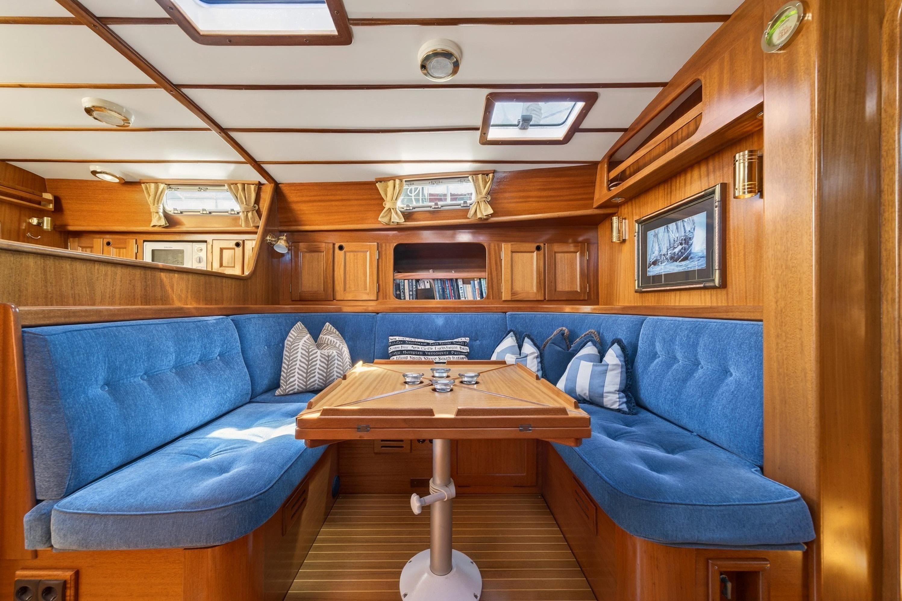 Cozy Malo 42 yacht interior with blue seating, wooden table, and nautical decor, 1997 model.