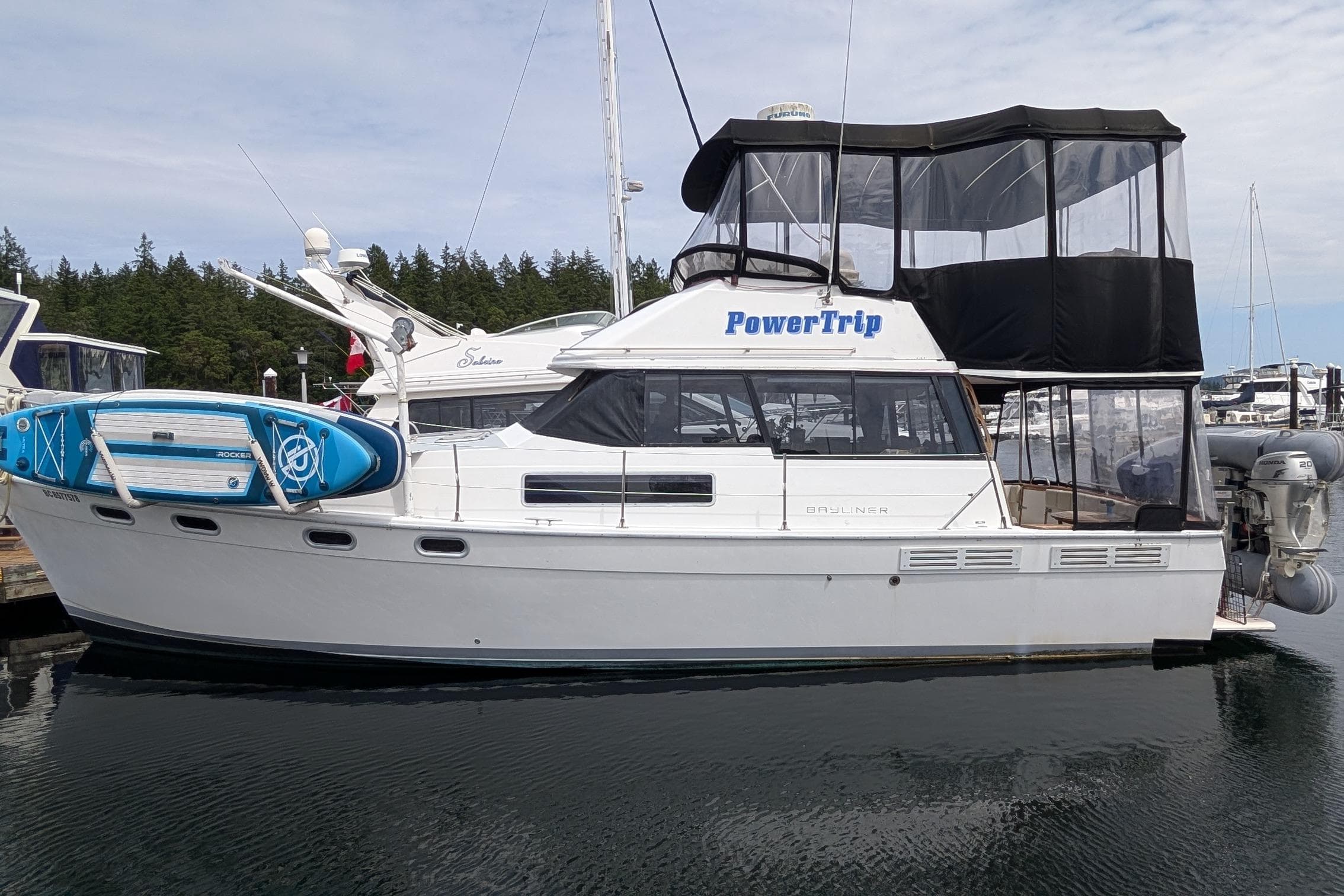 1990 Bayliner 3888 Motoryacht docked with paddleboards, named "PowerTrip."