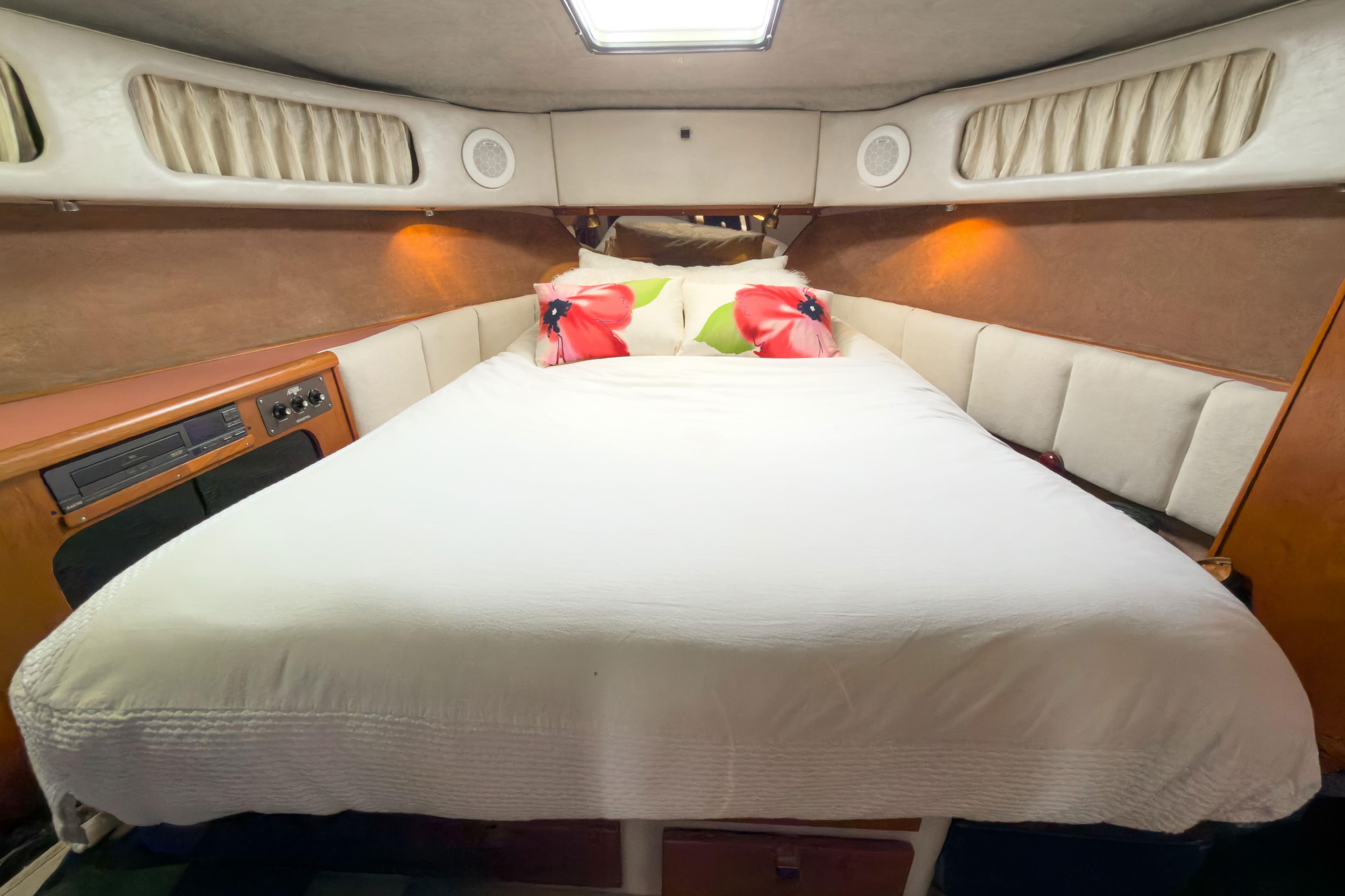 Cozy bedroom in 1987 Bayliner 3870 Motoryacht with white bedding and floral pillows.