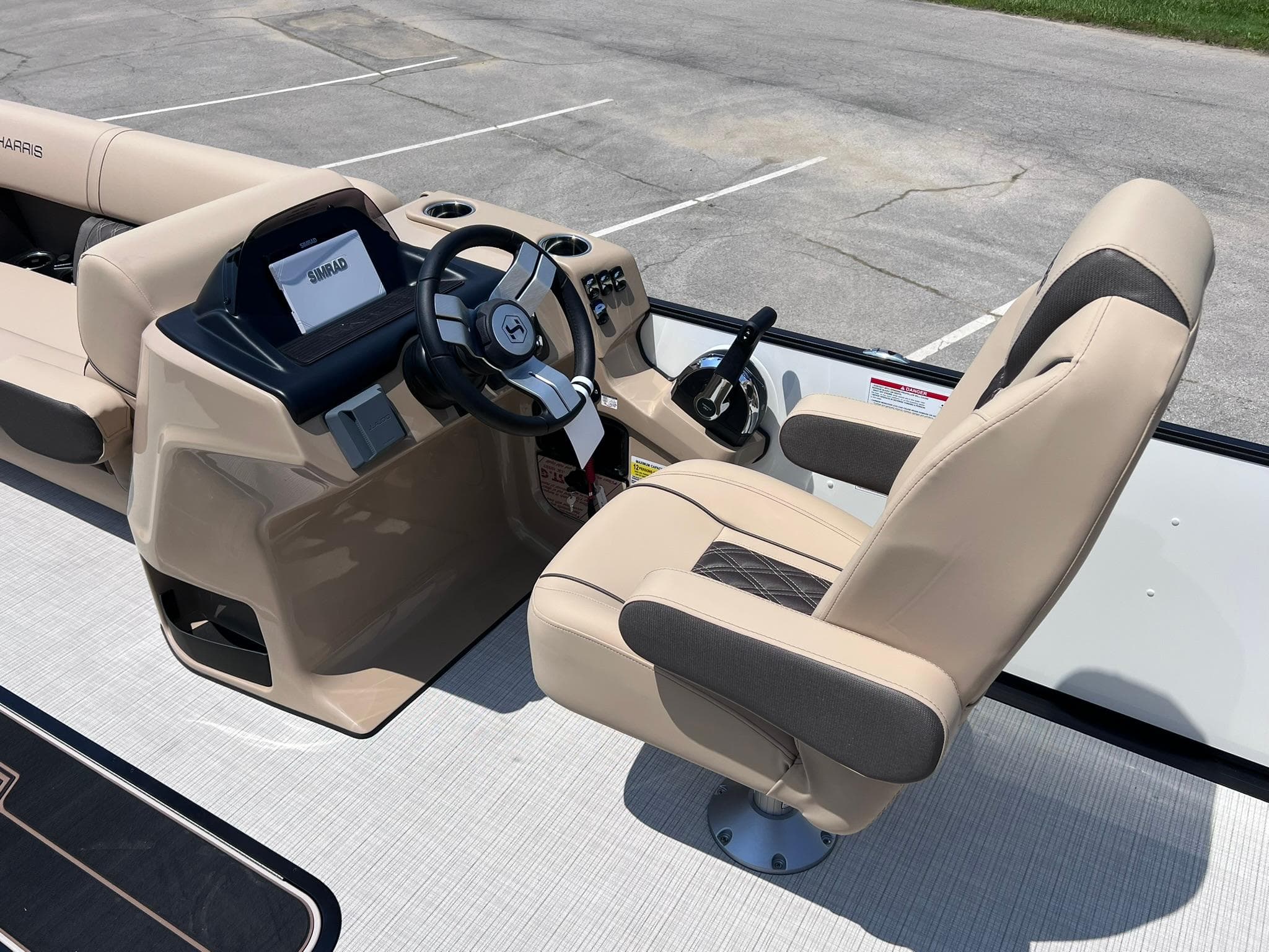 2025 Harris Sunliner 230 boat interior with beige captain's chair and control console.