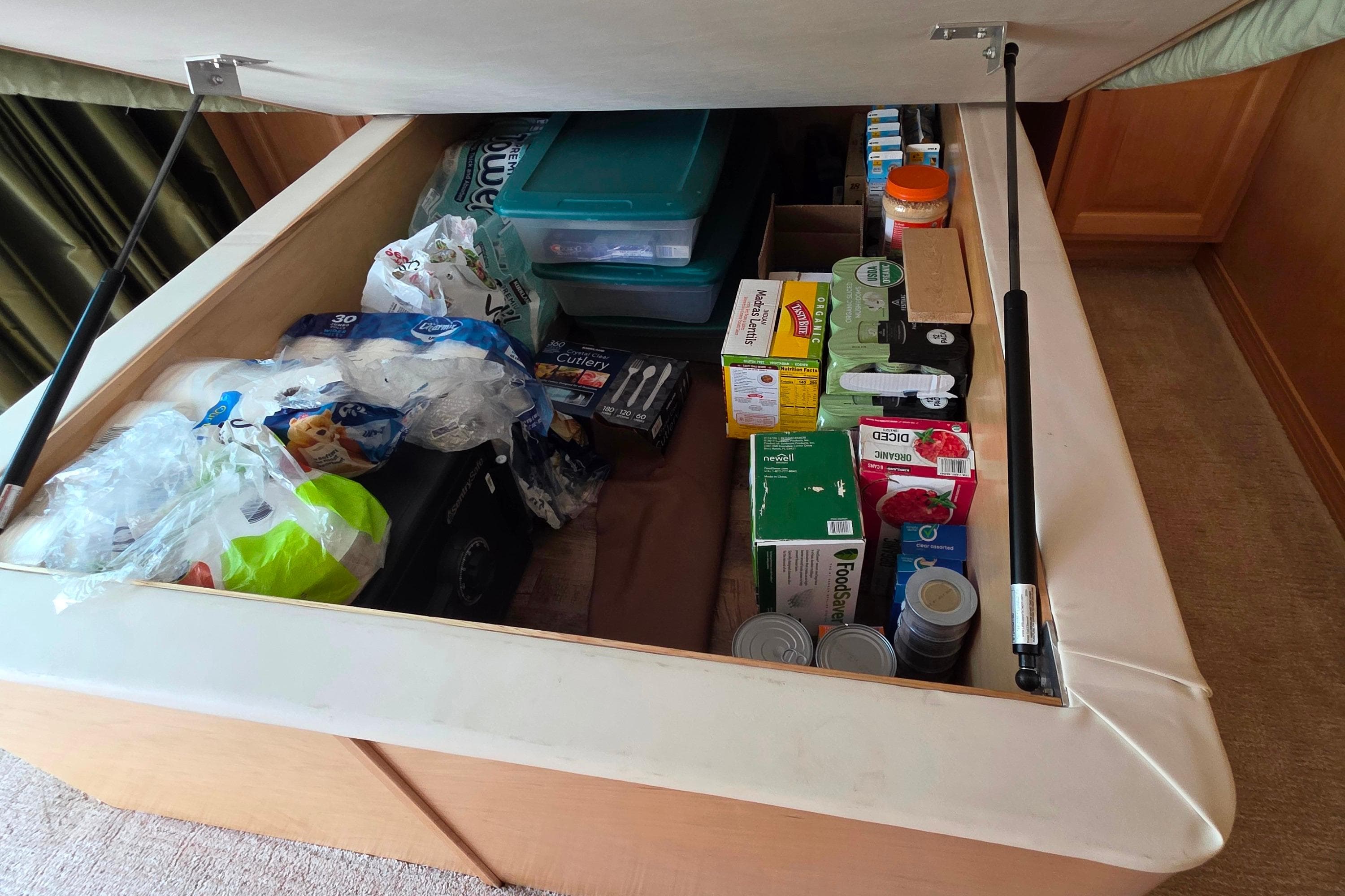 Under-bed storage in 2015 Sailabration 64, filled with household supplies and canned goods.