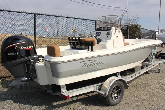 2025 Pioneer 180 Sportfish boat on trailer with Yamaha engine, parked near a fence.