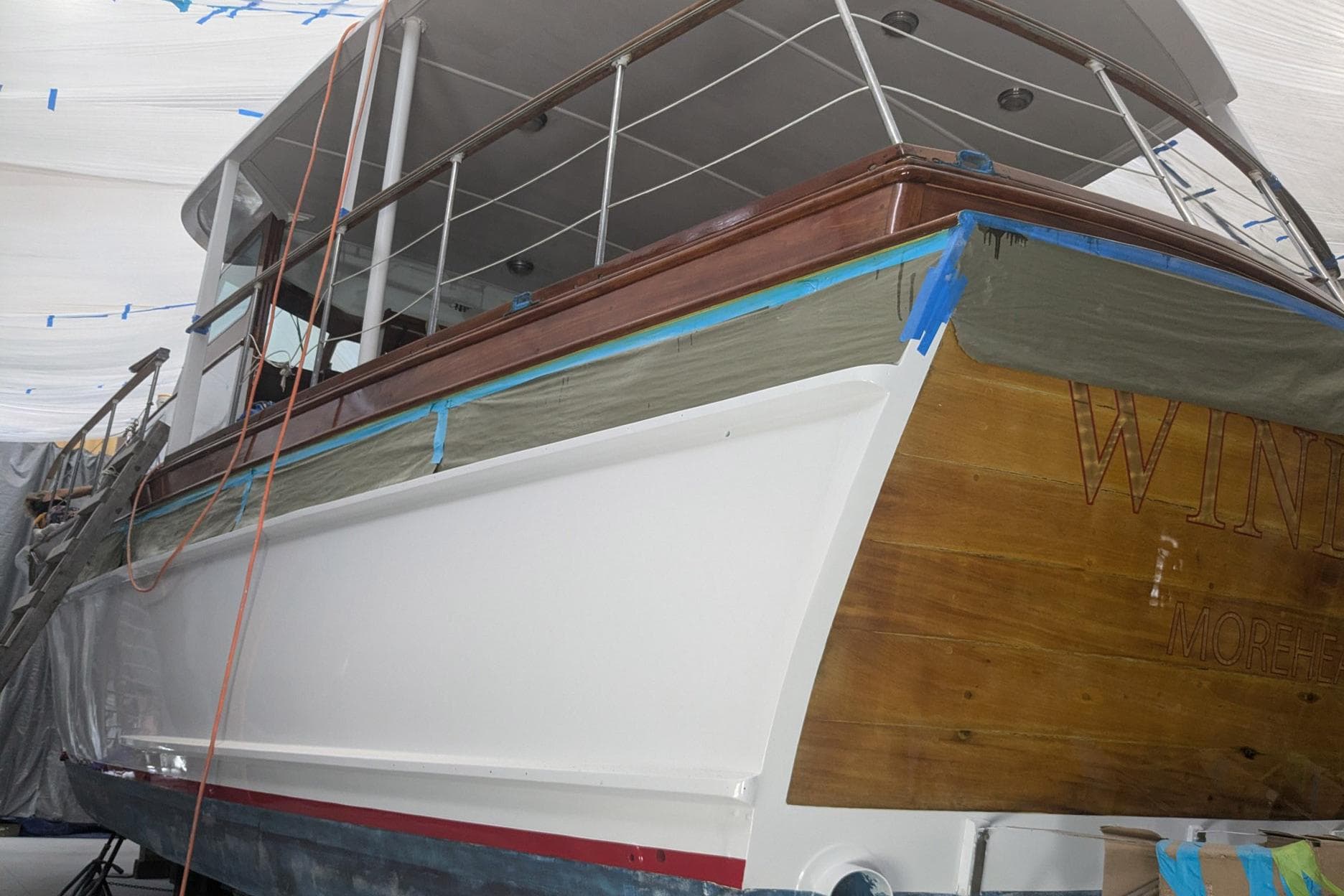 Restoration of a 1966 Trumpy 55 yacht with wooden and white painted hull.