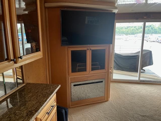 Interior of 2001 Stardust Cruisers houseboat with TV, cabinets, and sliding glass doors.