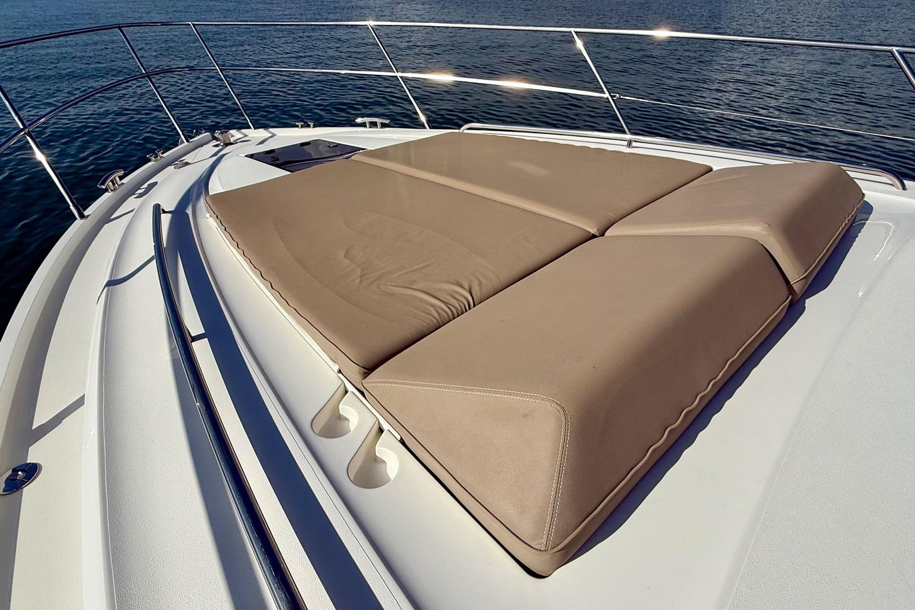 Luxury sunbed on 2015 Princess V48 yacht deck, overlooking serene water.