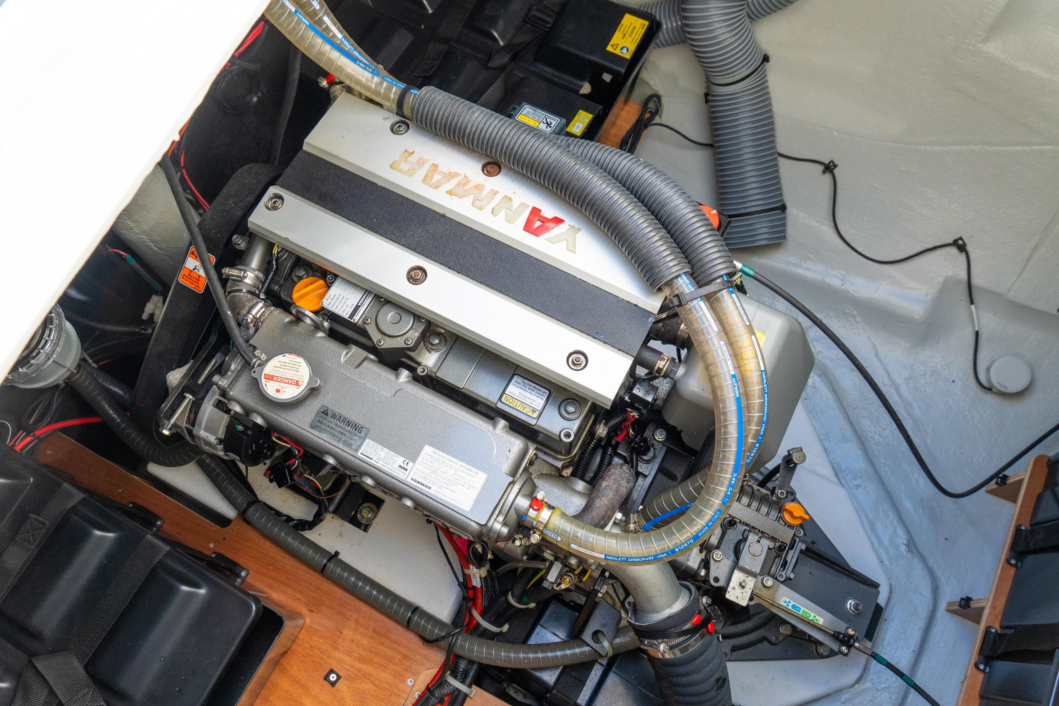 Engine compartment of 2023 Lagoon 46 yacht, featuring a Yanmar engine with visible hoses and components.