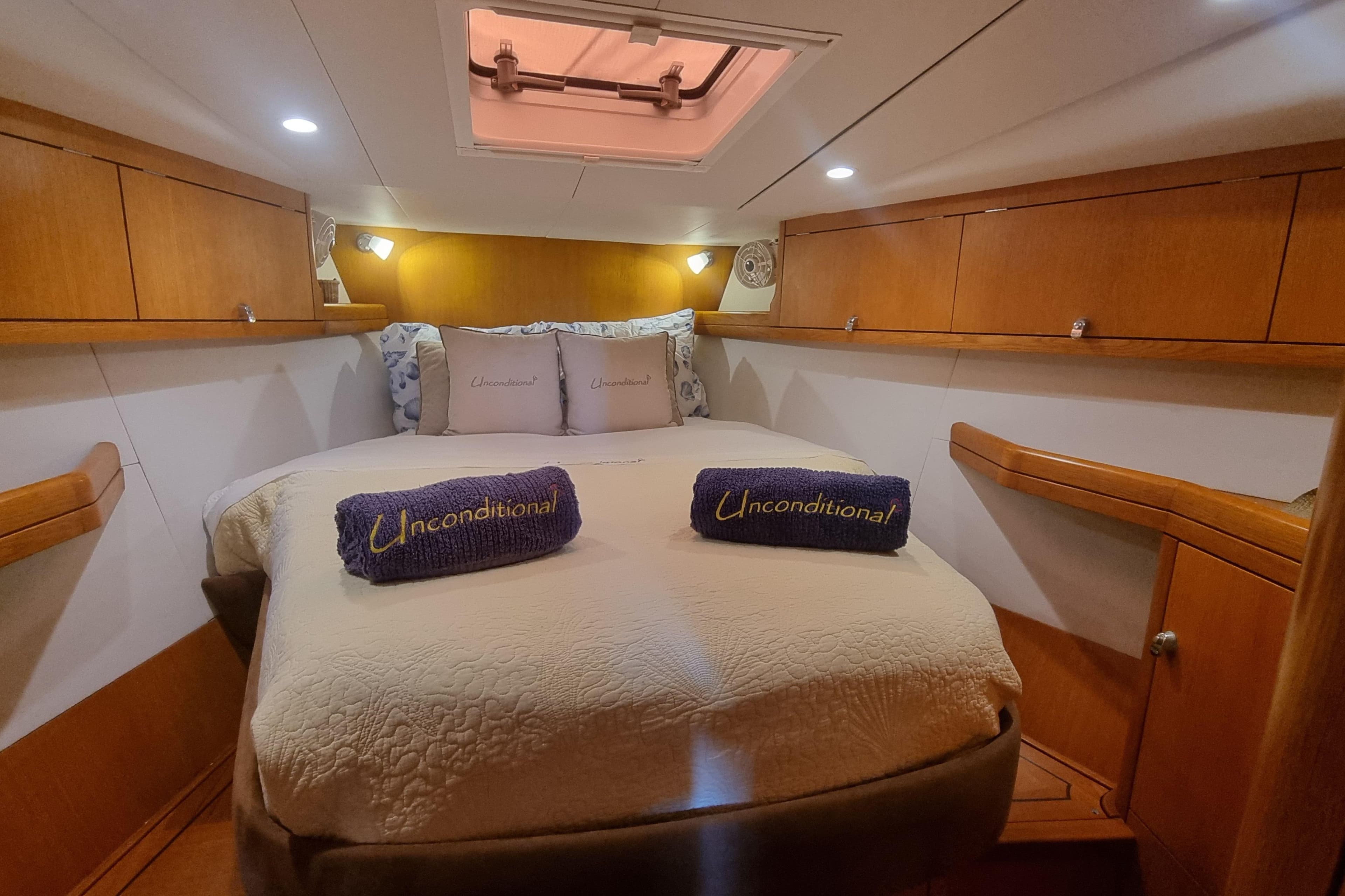 Luxurious cabin interior of 2004 Oyster 49 yacht with cozy bedding and wooden accents.