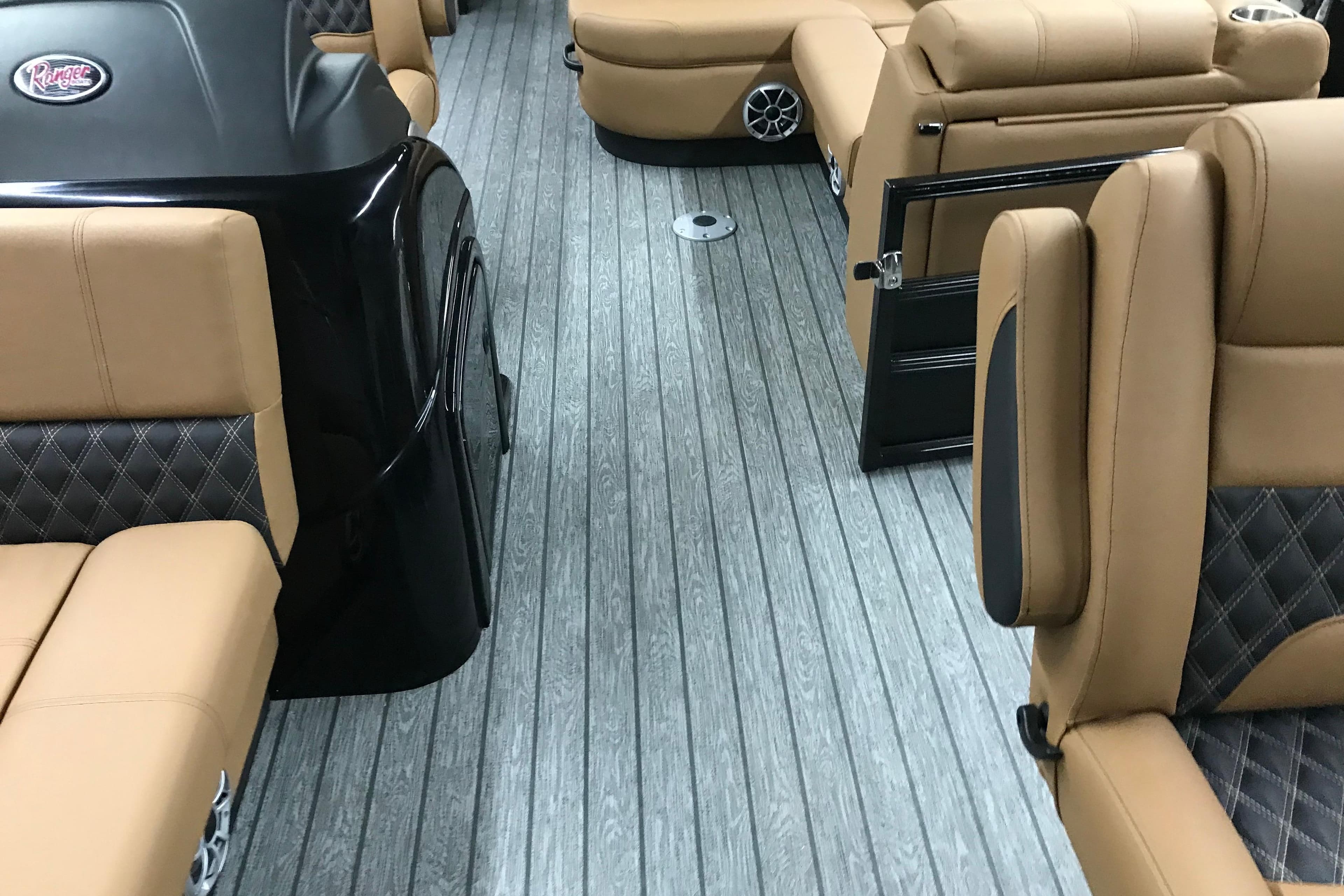 Luxurious interior of 2026 Ranger Reata 220FC boat with tan leather seating and wood-style flooring.