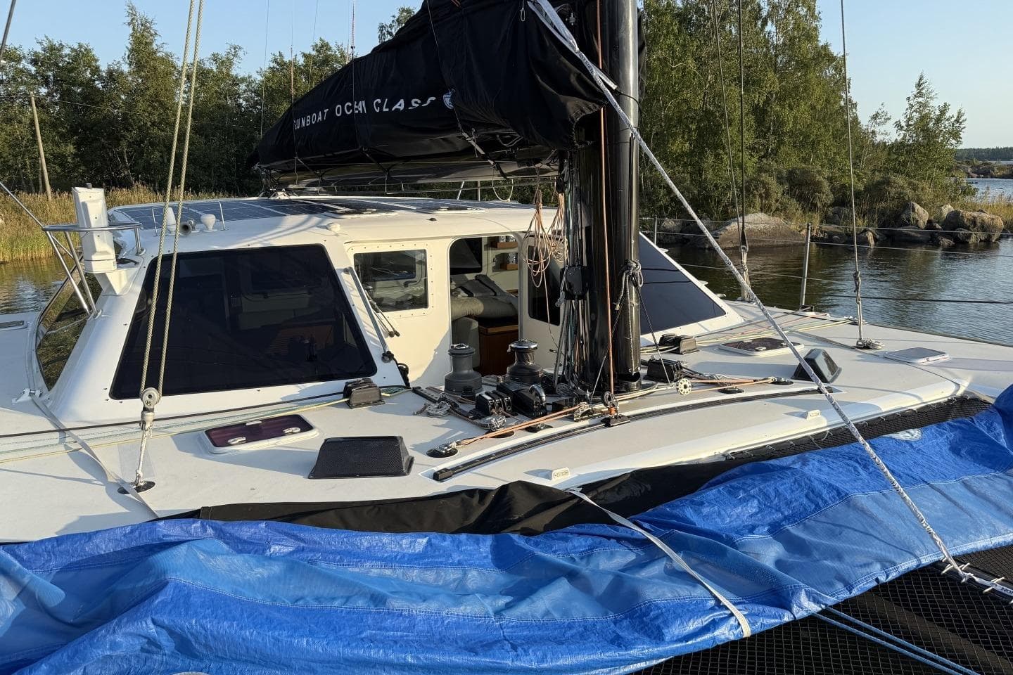 2006 Gunboat 48 catamaran docked by a serene lakeside with lush greenery.
