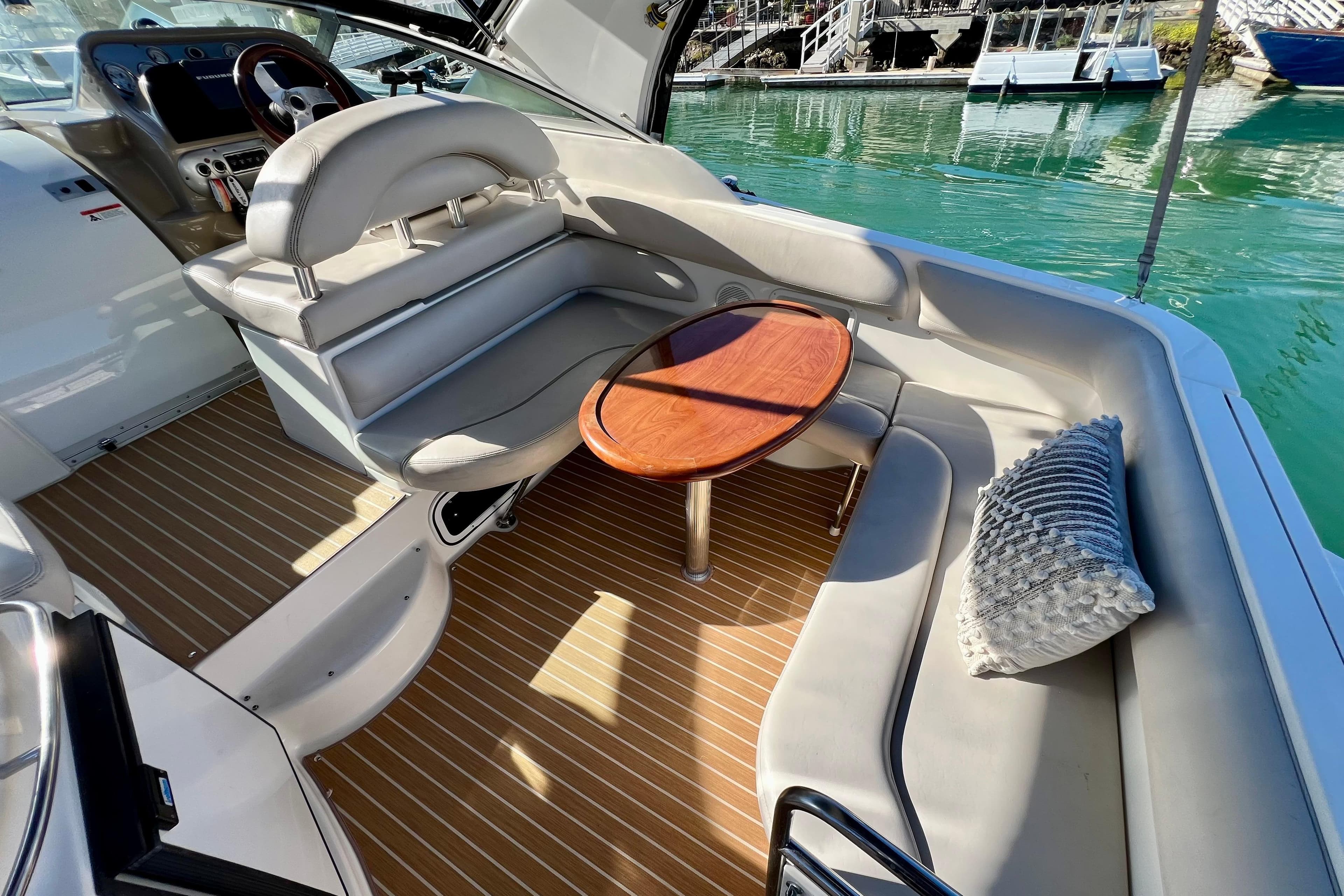 2007 Larson Cabrio 310 boat interior with seating, table, and cushion, docked by the water.