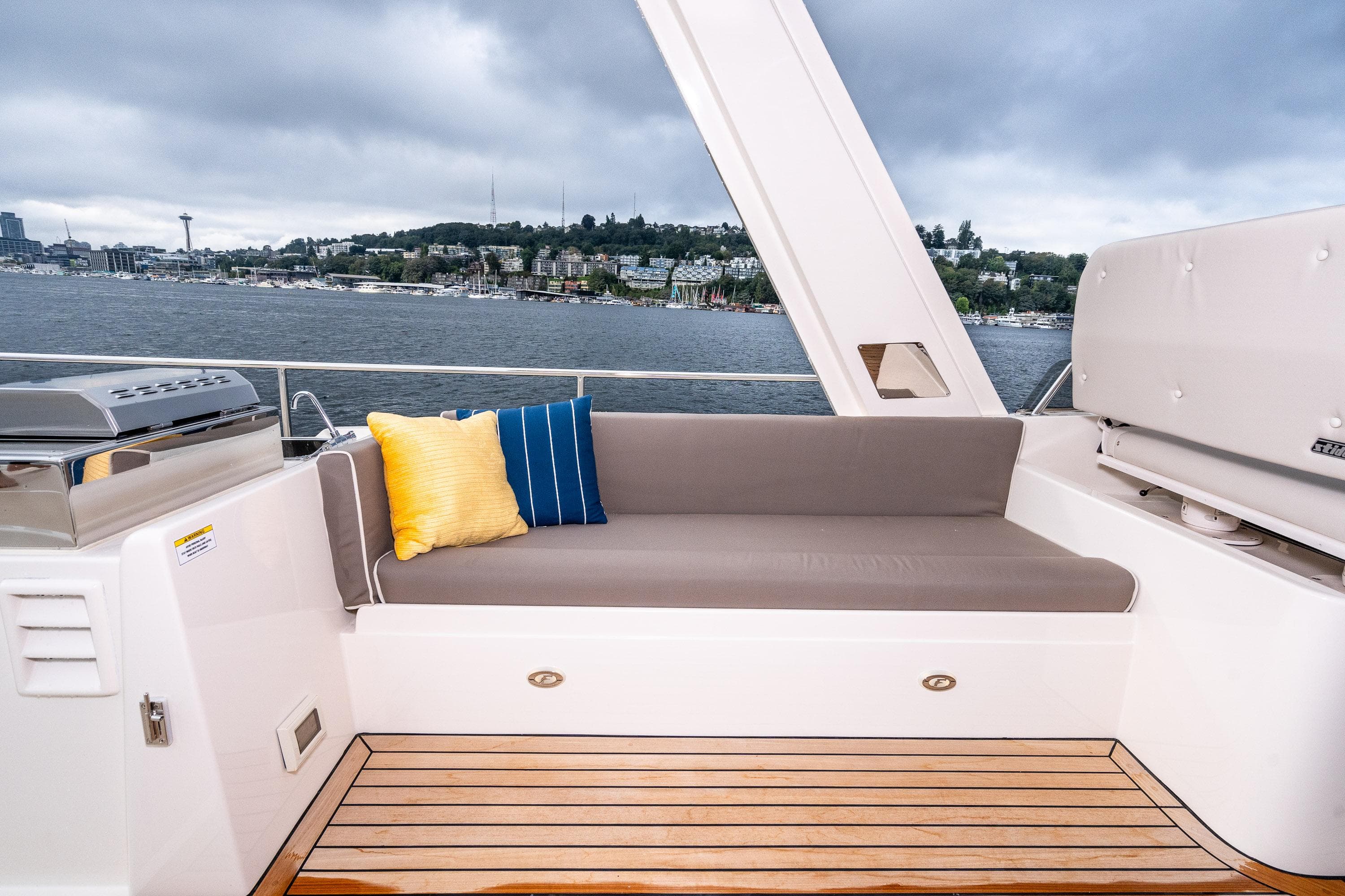 2024 Fleming 58 Pilothouse yacht with cushioned seating and scenic waterfront view.