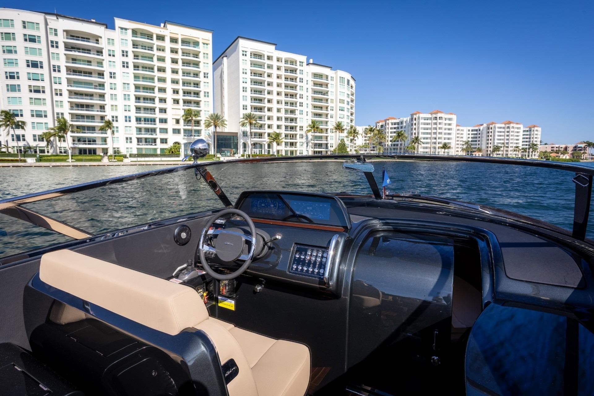 2025 Riva 33' Aquariva Special yacht cruising near waterfront buildings under clear blue sky.