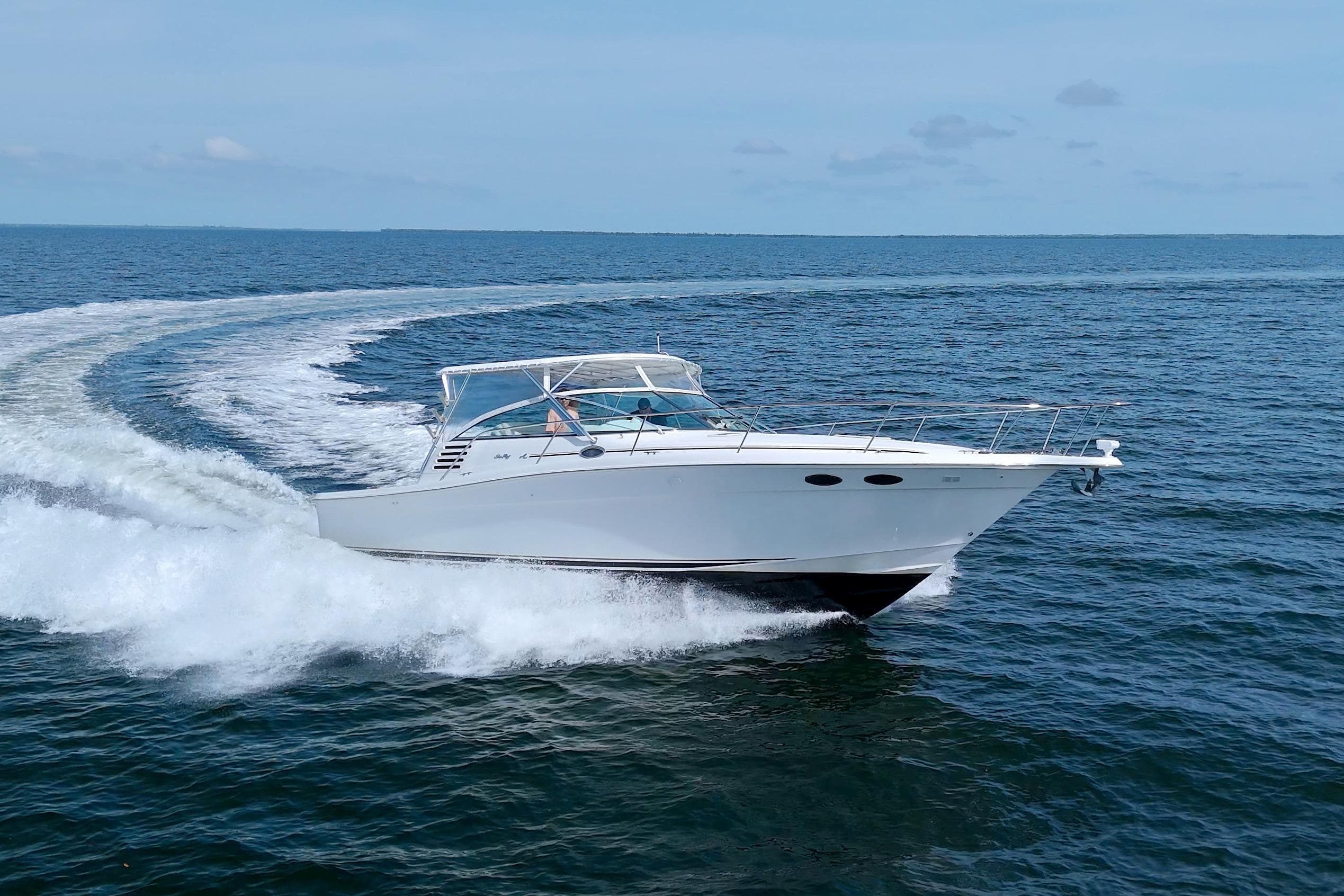 1997 Sea Ray 370 Express Cruiser speeding on open water, creating a dynamic wake.