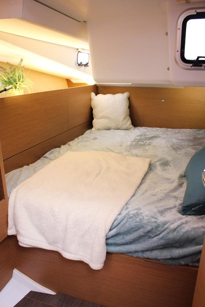 Cozy cabin interior of 2025 Jeanneau Sun Odyssey 440 sailboat with plush bedding.