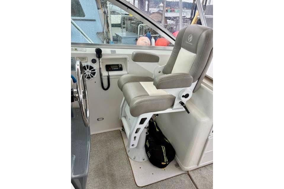 Captain's chair in 2000 Pursuit 3400 Express boat cockpit, featuring control panel and steering wheel.