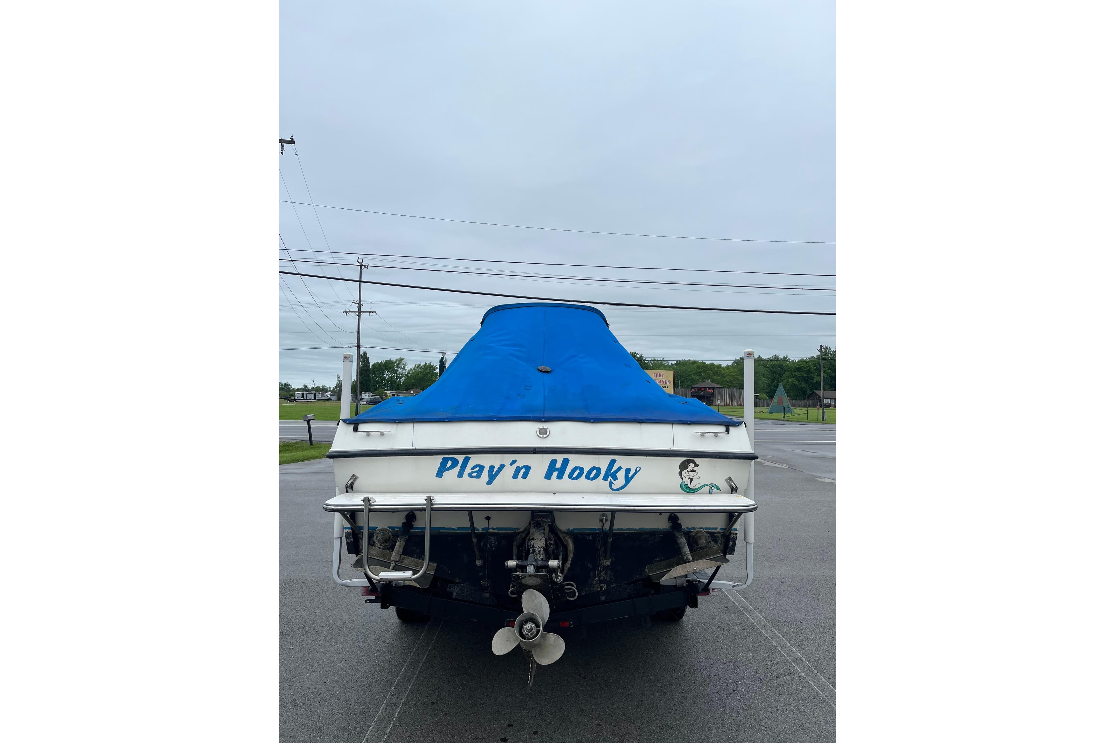 1995 Celebrity 2500 Fish Hawk boat with blue cover, named "Play'n Hooky."