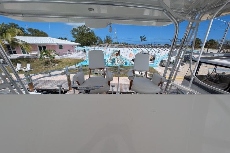 2005 Egg Harbor 43 SportYacht helm with white chairs, docked near tropical setting.
