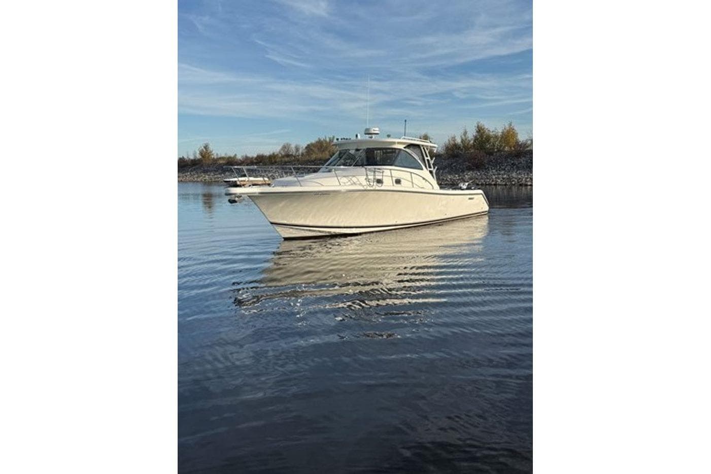 2009 Pursuit OS 375 Offshore boat on calm water under a clear blue sky.