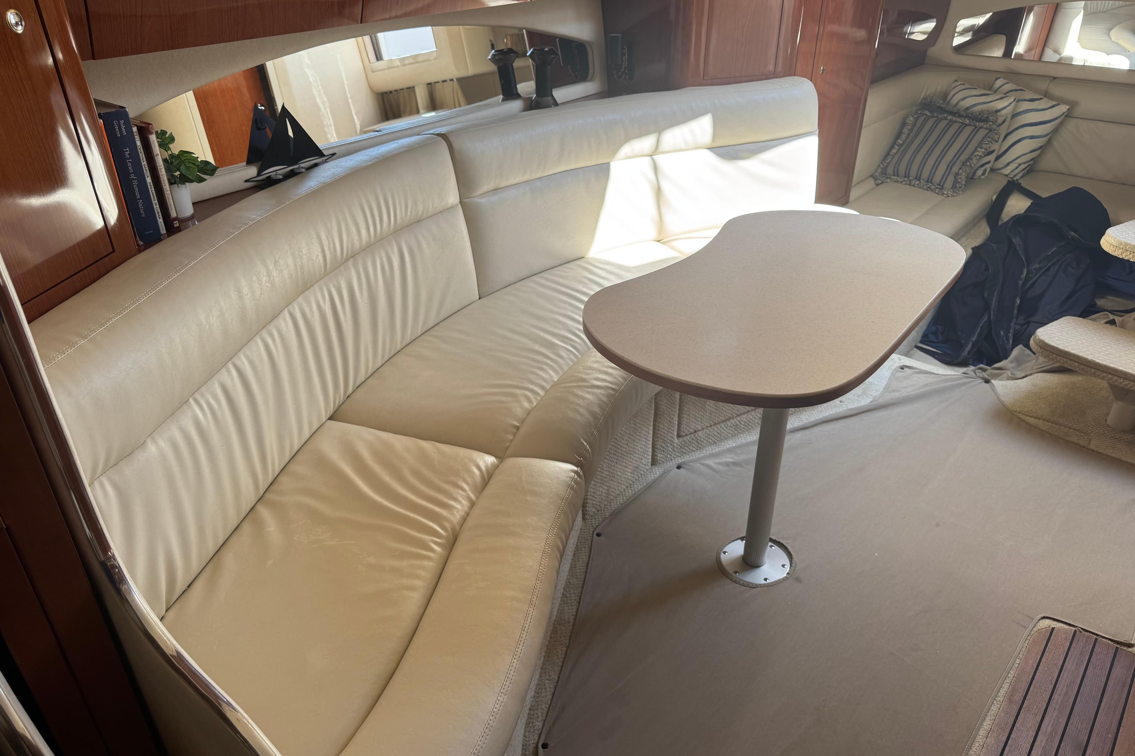 Interior of 2002 Sea Ray 360 Sundancer with cream leather seating and wooden table.