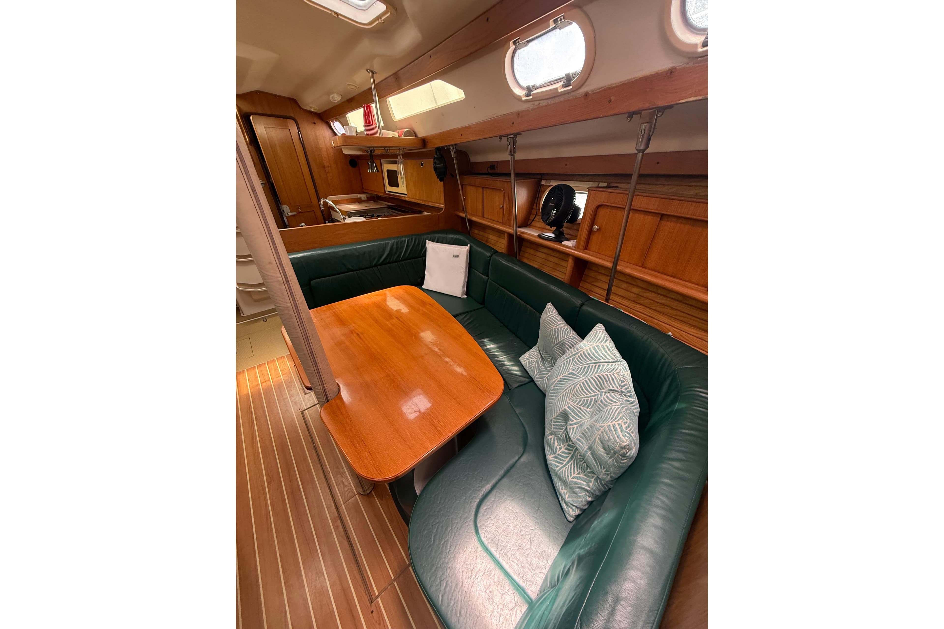 Interior of 2001 Catalina 390 sailboat with green seating and wooden table.