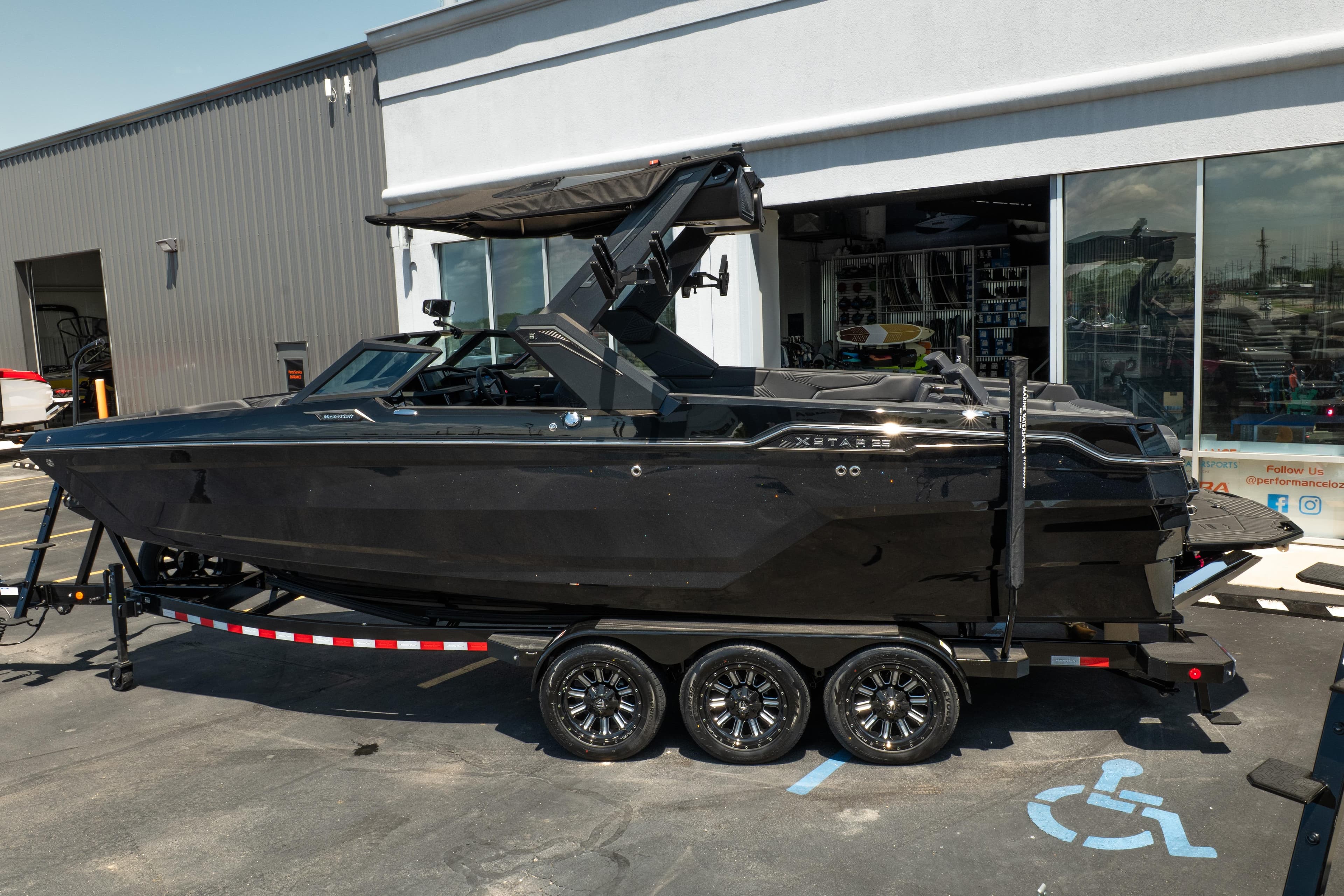 2026 MasterCraft XStar 25 boat on trailer, parked outside a showroom.