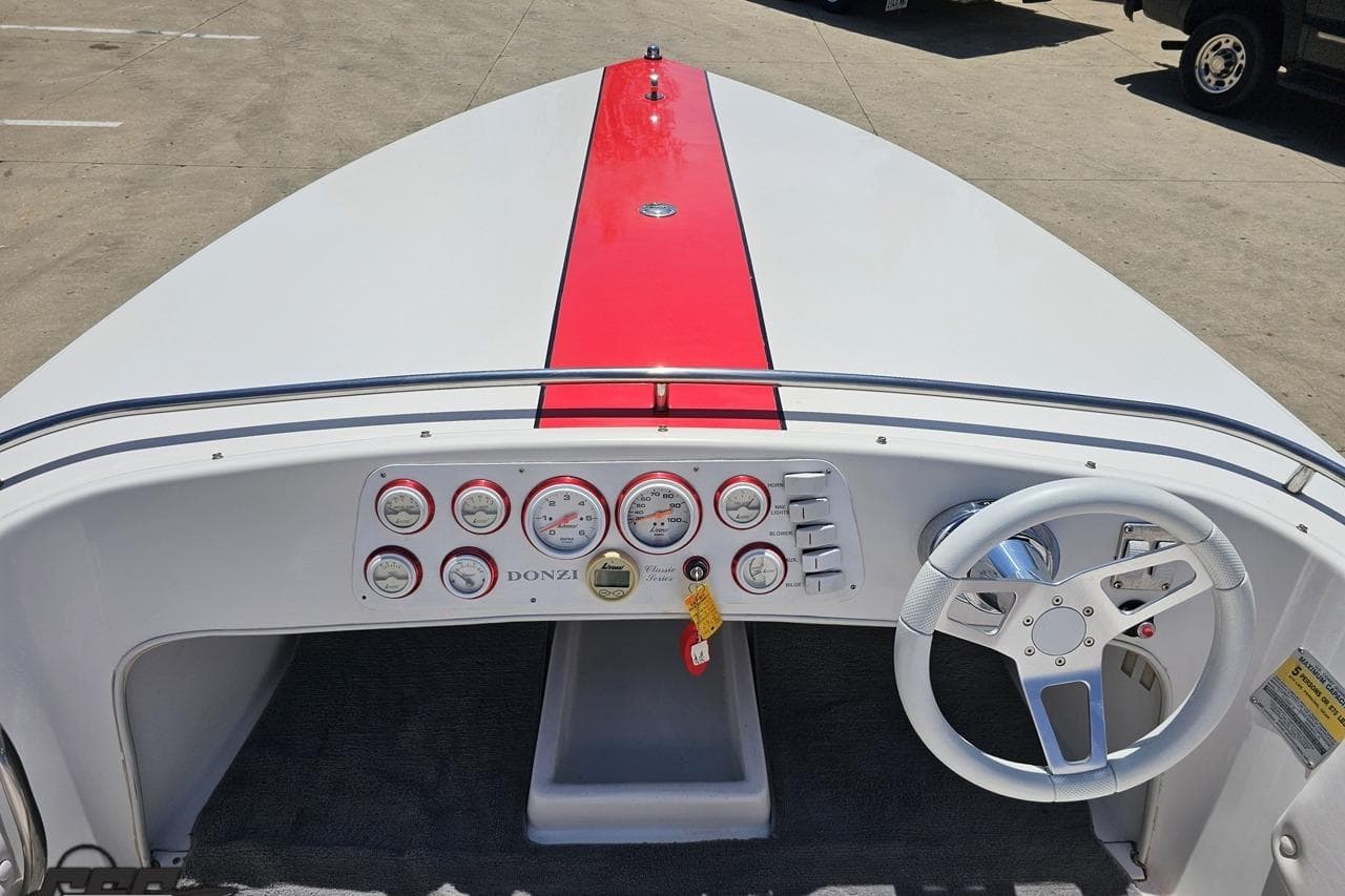 1997 Donzi 18 Classic boat dashboard with red stripe, gauges, and white steering wheel.
