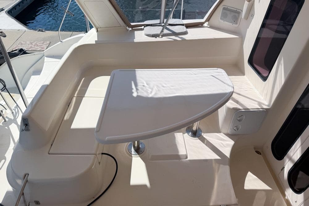 Leopard 38 catamaran cockpit with seating and table, 2000 model, docked by the water.