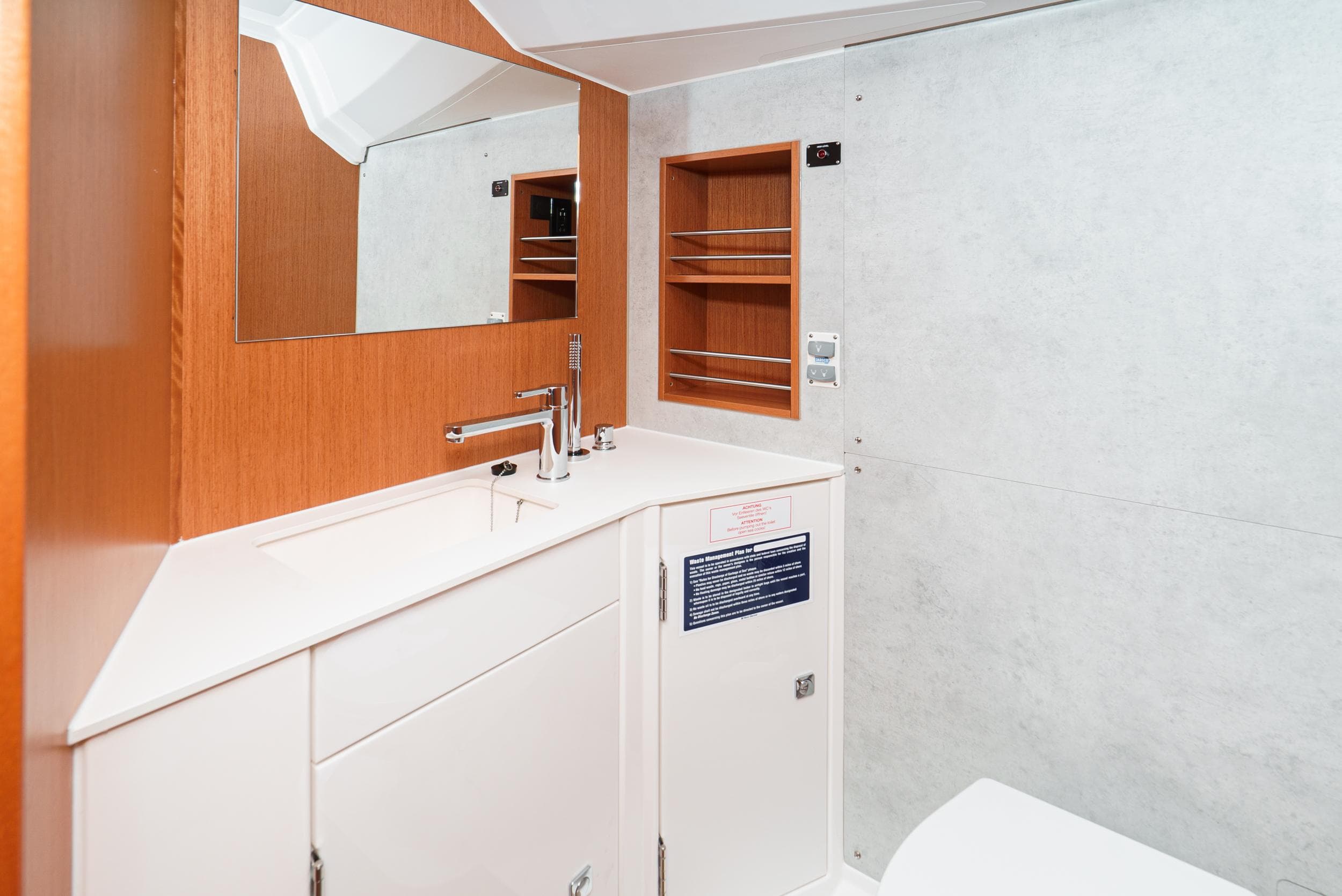 2024 Bavaria C42 yacht bathroom with modern sink, mirror, and wooden cabinetry.