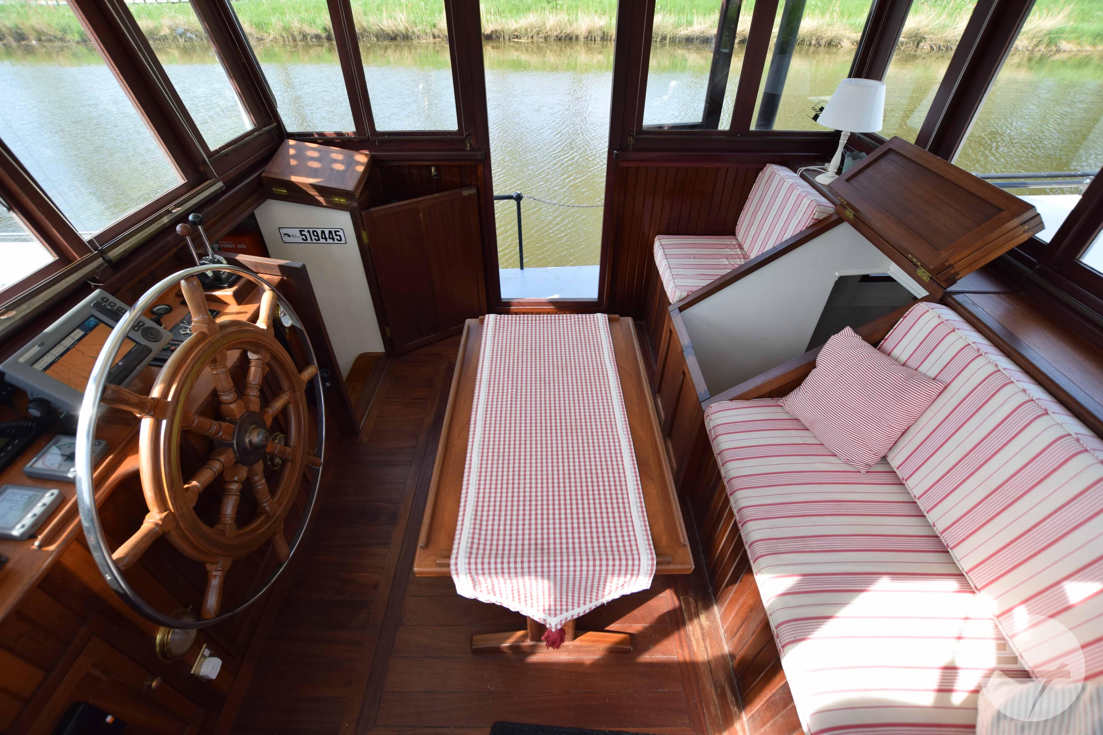 Interior of a 2010 Custom Dutch Barge Replica with wooden helm and striped seating.