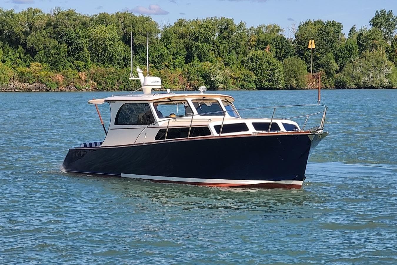 2006 Marlow 375 Prowler Classic boat cruising on a serene lake with lush green shoreline.