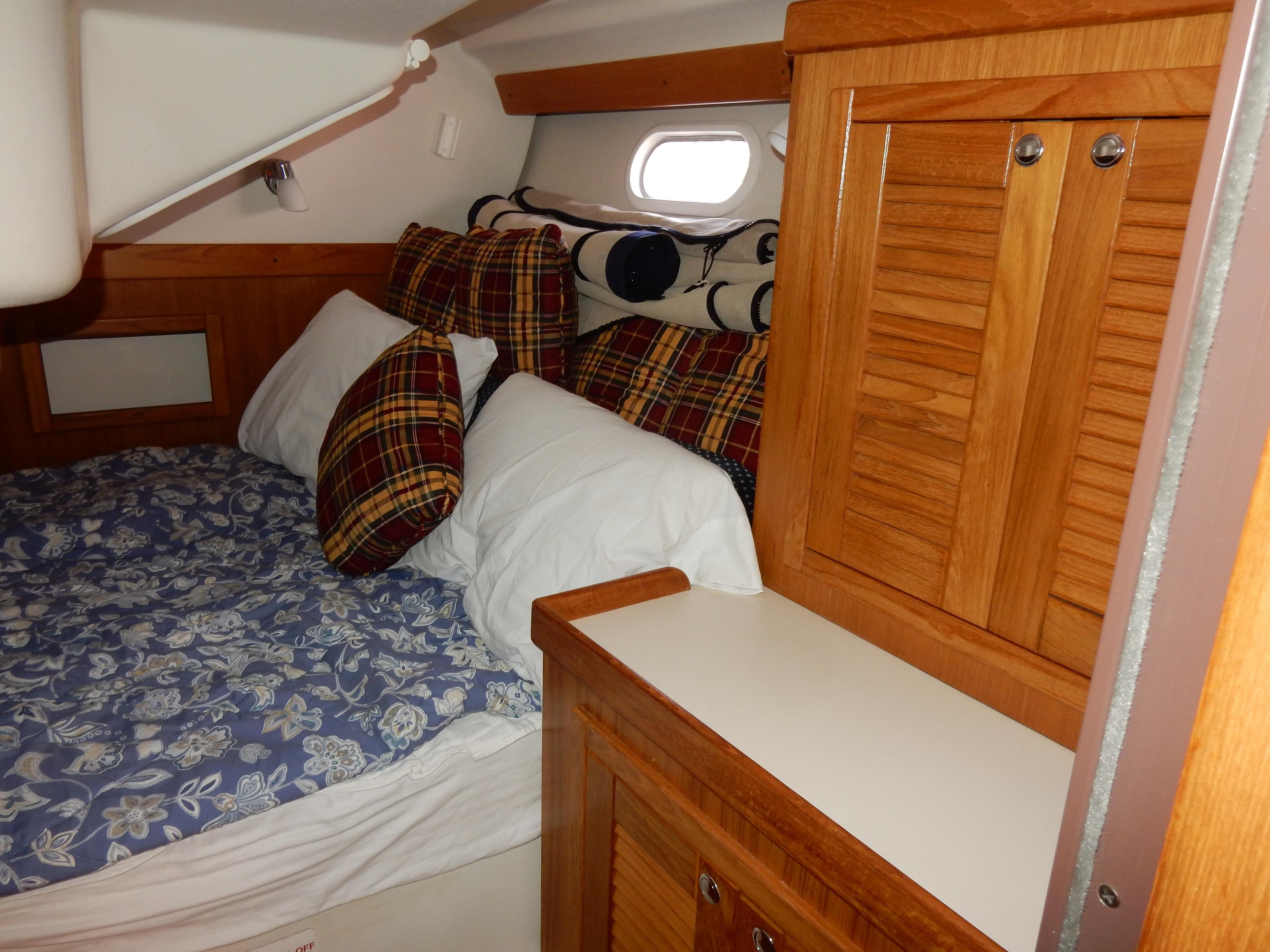 Cozy cabin interior of 2004 Catalina 350 sailboat with plaid pillows and wooden cabinetry.