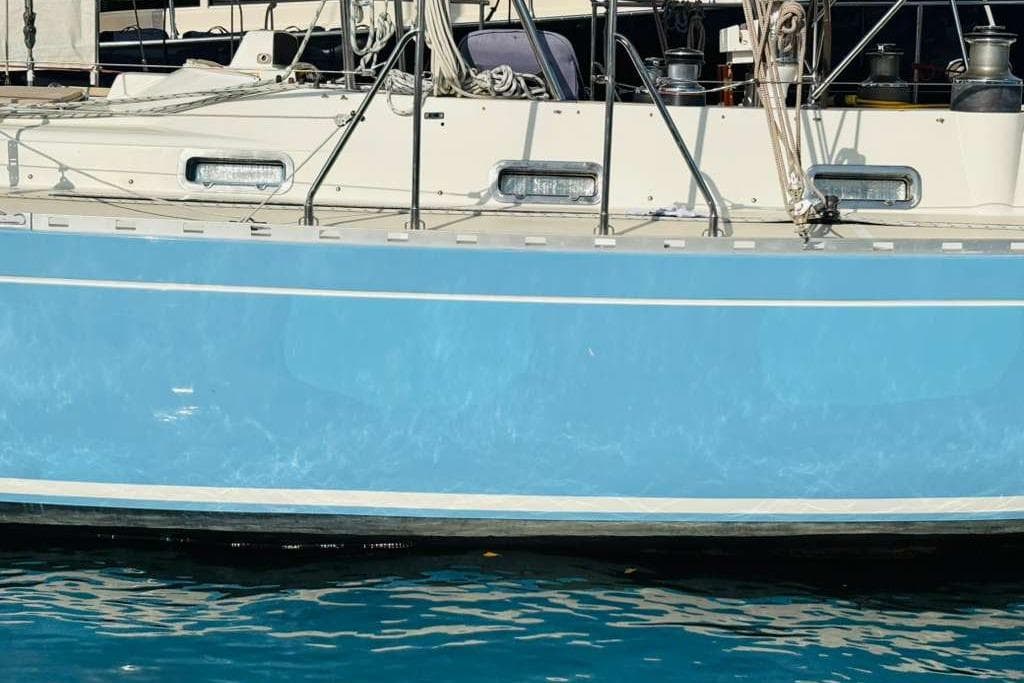 Blue hull of 1982 Steven Custom Stevens 47 sailboat docked in calm water.