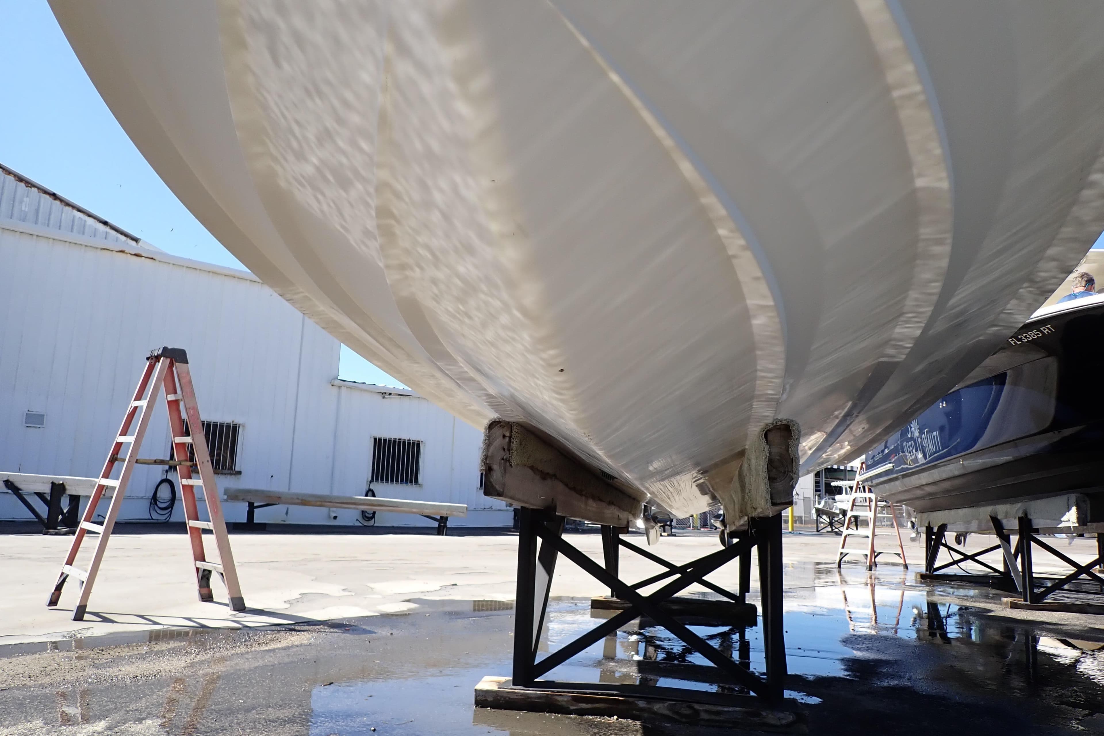 2014 Pro-Line 32 Express boat hull on stands, with ladder nearby in a boatyard.