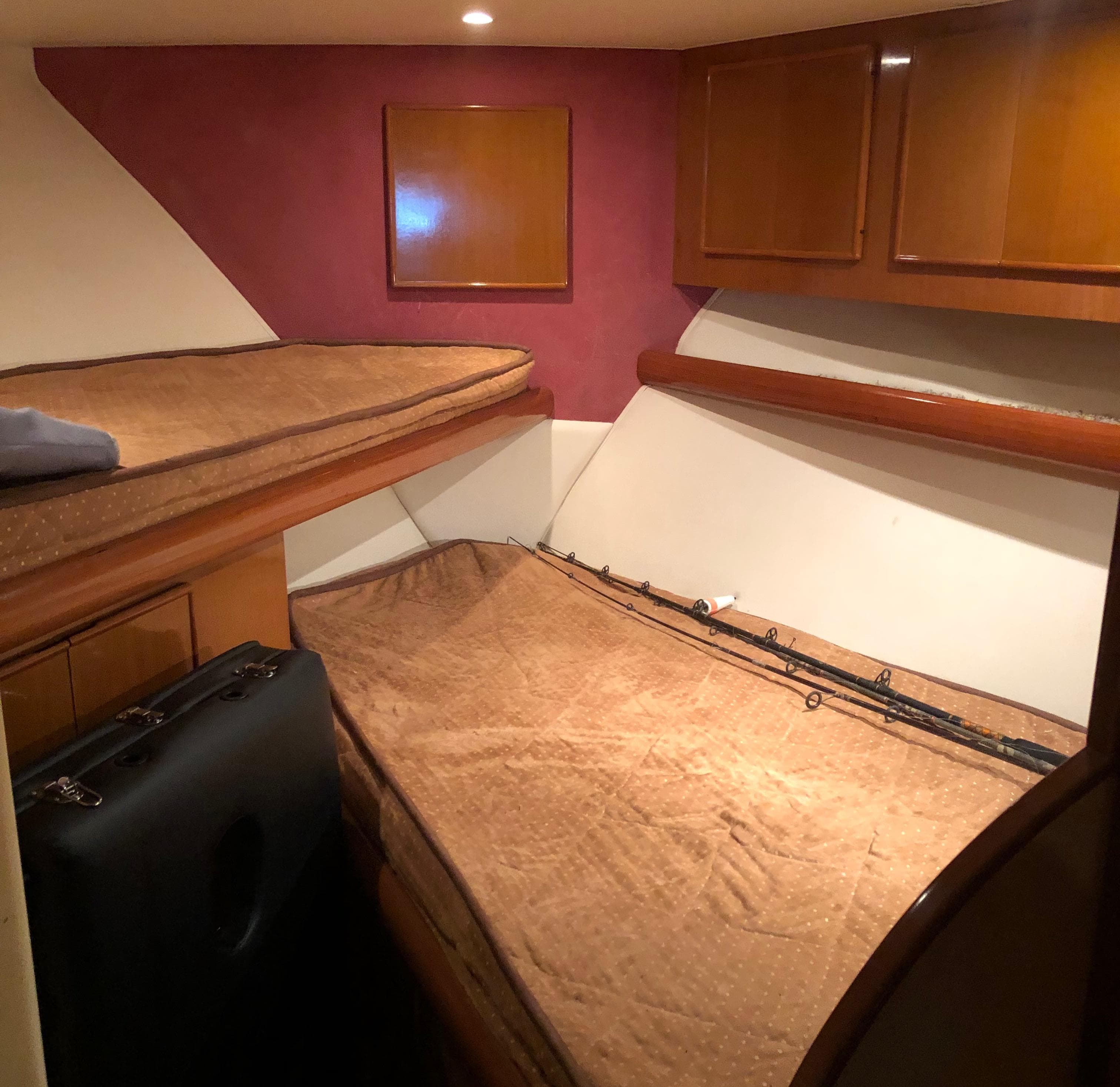 Cozy cabin interior of a 1999 Post 50 boat with bunk beds and wooden cabinets.