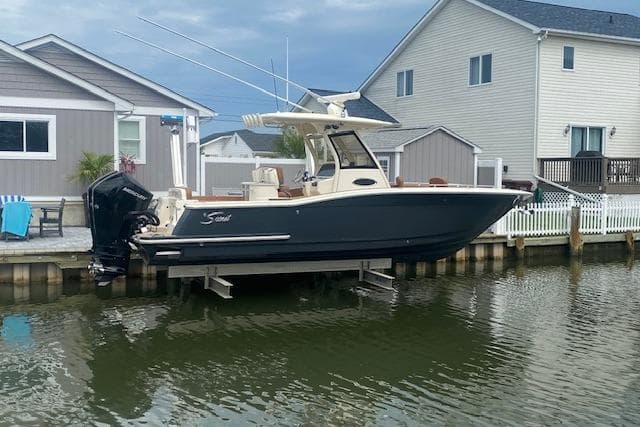 2023 Scout 277 LXF boat docked by waterfront homes.