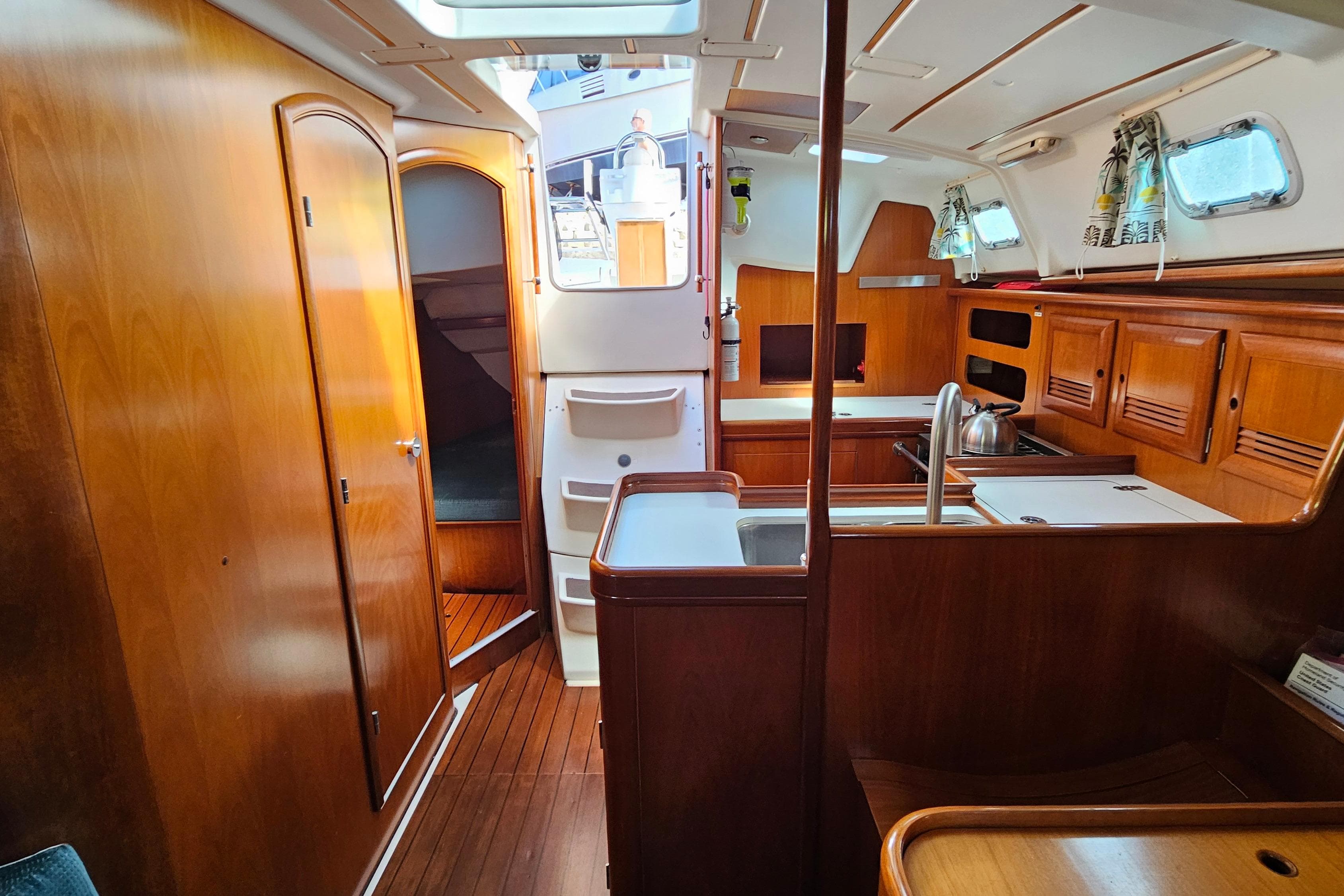 Interior of 2000 Beneteau Oceanis Clipper 361 yacht, featuring wood cabinetry and compact kitchen.