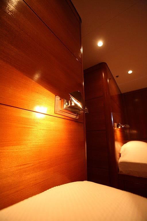 Luxurious wooden interior of 2008 Nautor Swan 90 FD yacht cabin, warmly lit ambiance.