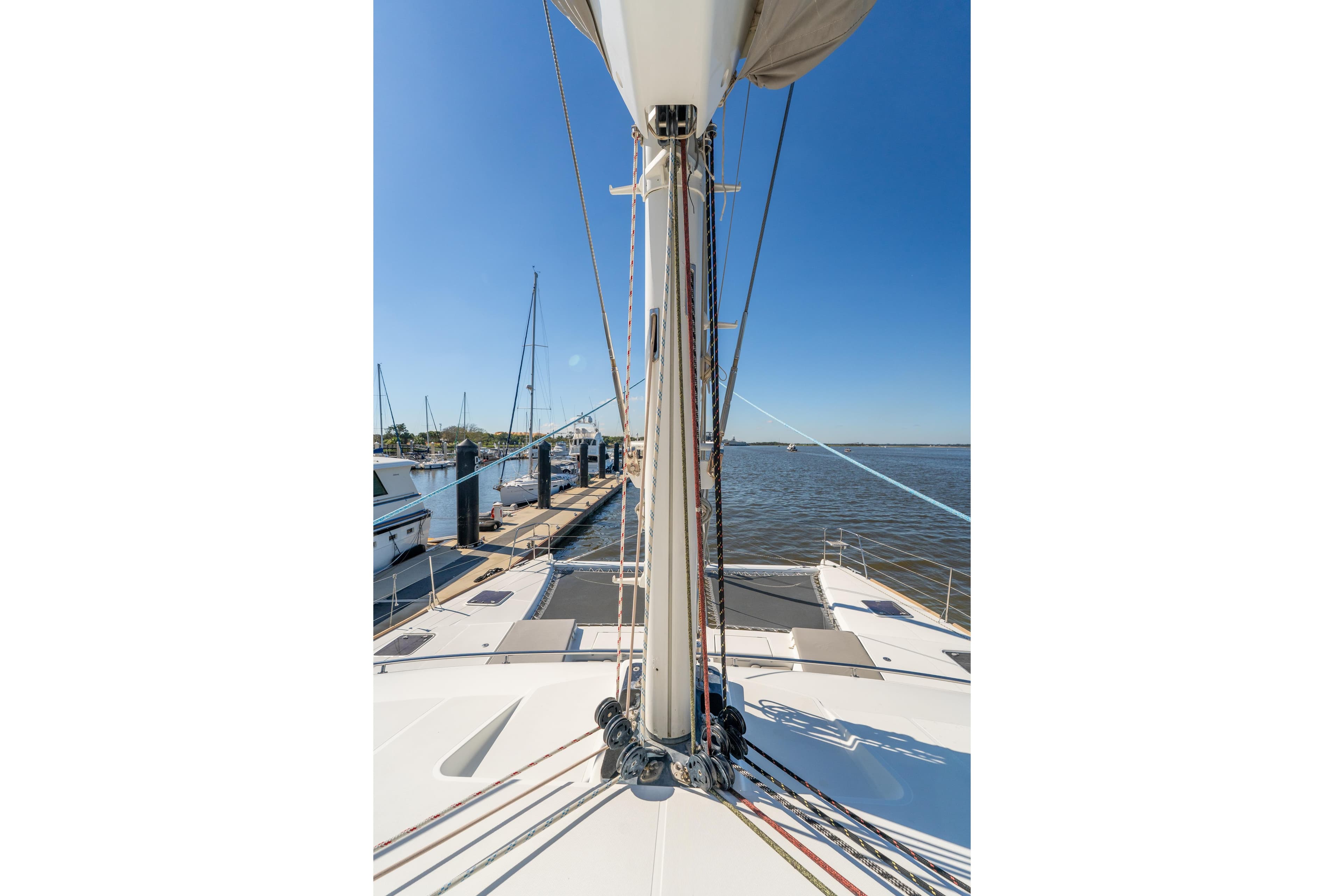 Lagoon 560 catamaran deck view, 2012 model, docked at marina under clear blue sky.