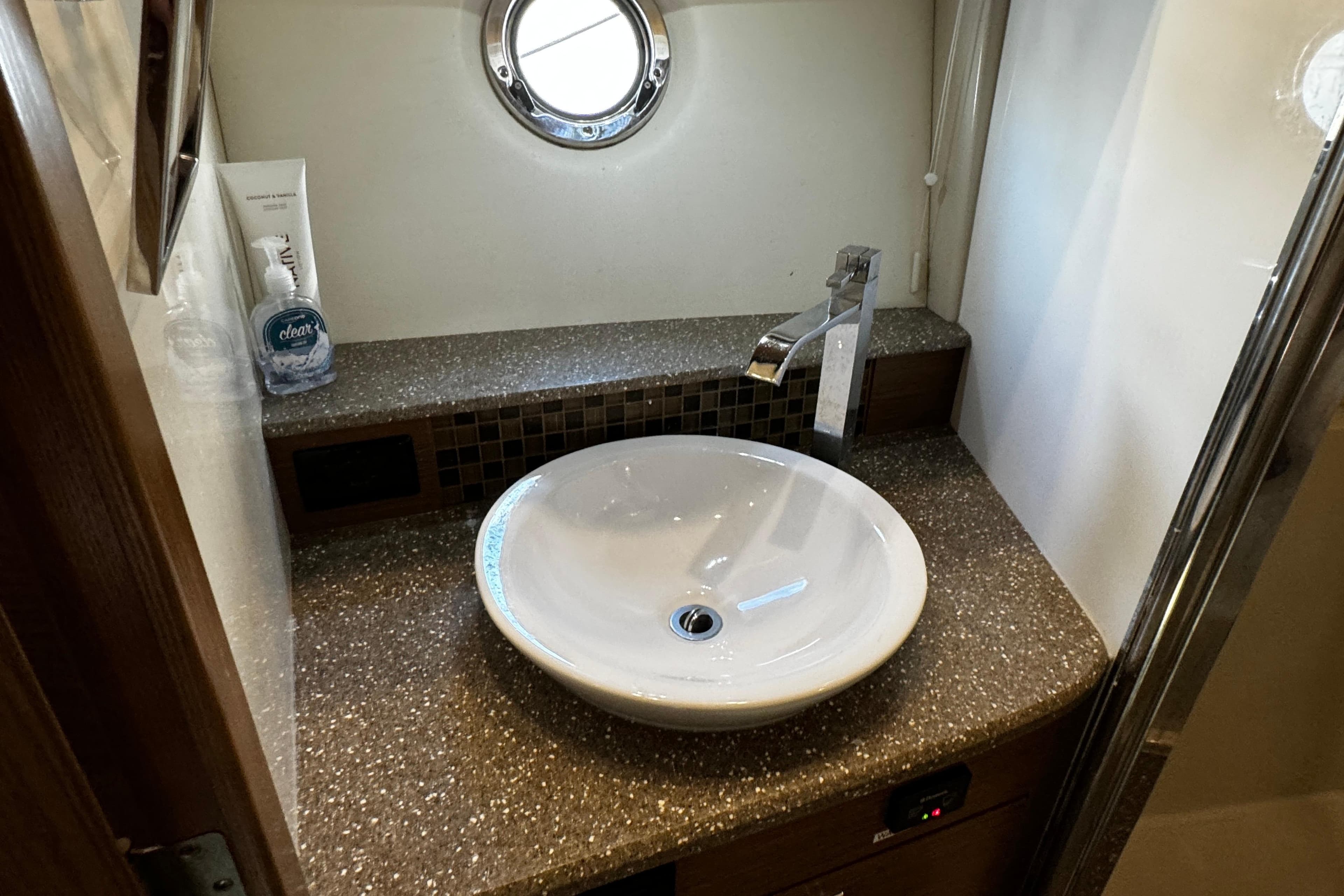 Bathroom sink area in 2014 Cruisers Yachts 45 Cantius, featuring modern fixtures and porthole window.