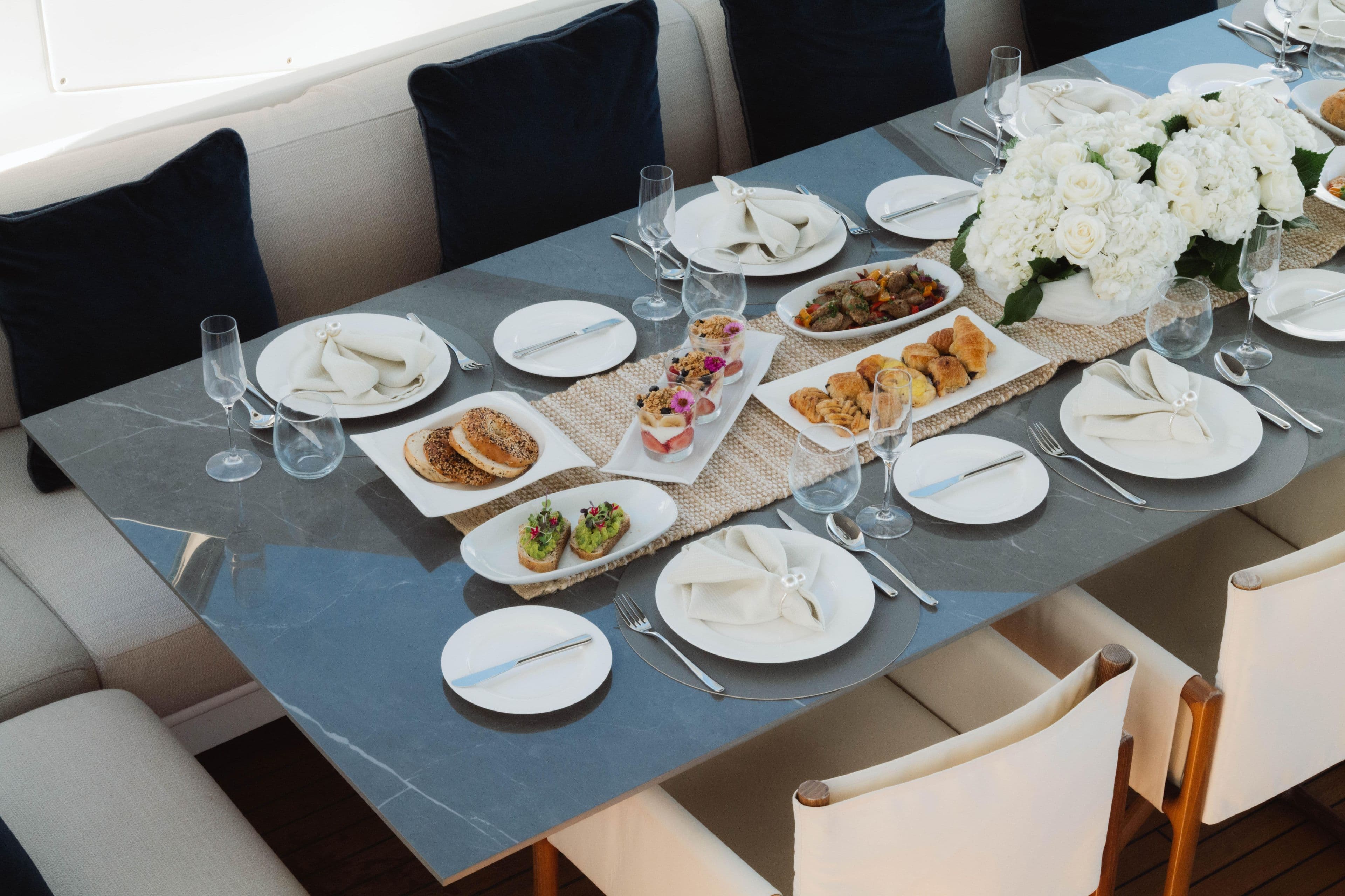 Elegant dining setup on Azimut yacht, featuring gourmet appetizers and floral centerpiece, 2023.