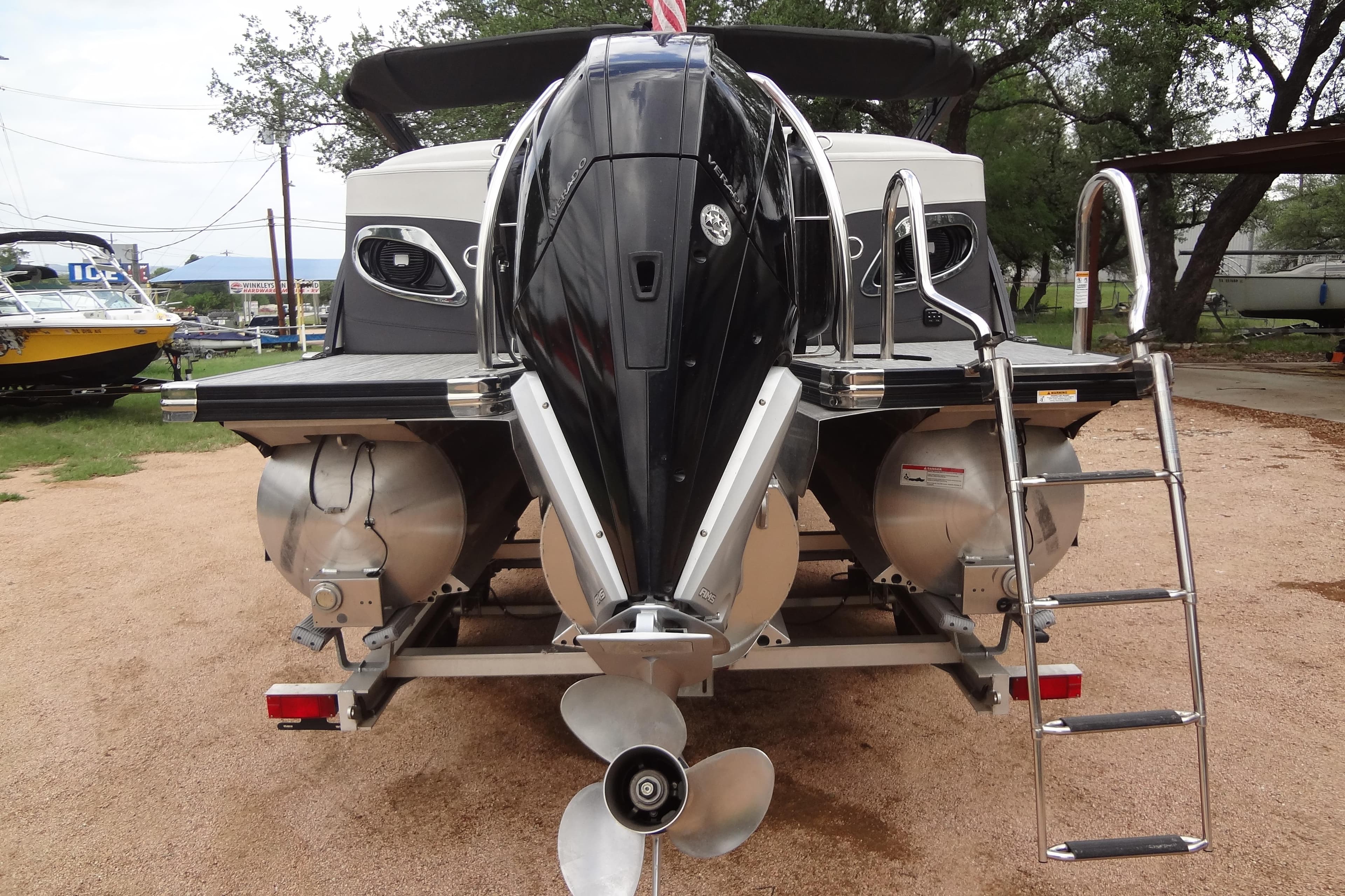 2021 Baraletta Corsa 23 QSS pontoon boat with outboard motor and ladder, parked outdoors.