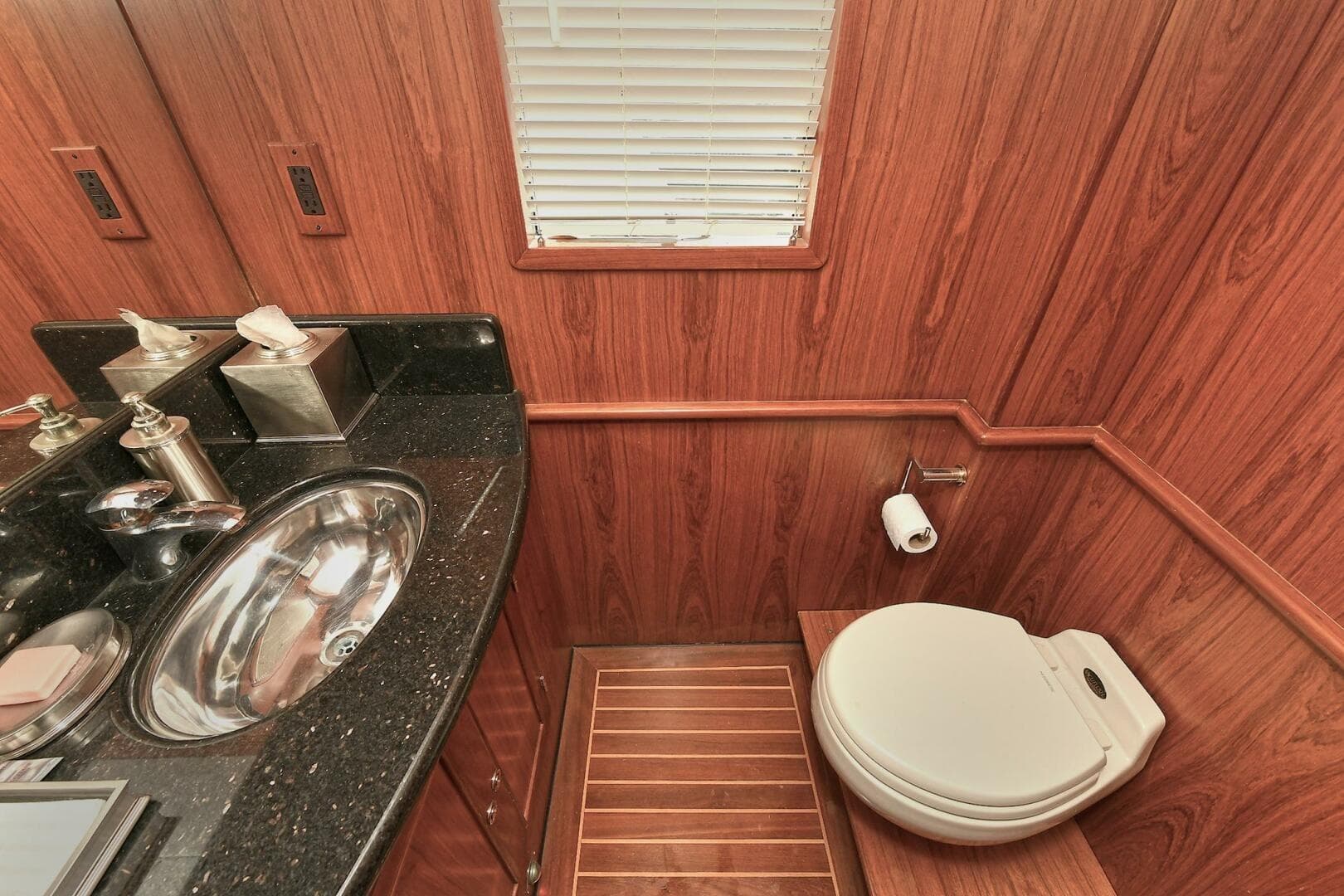 Luxurious 2002 Grand Alaskan Flushdeck yacht bathroom with wood paneling and modern fixtures.