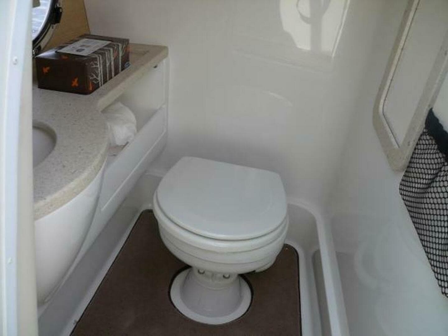 Compact bathroom in 2012 Cobalt 273 boat with toilet and sink.