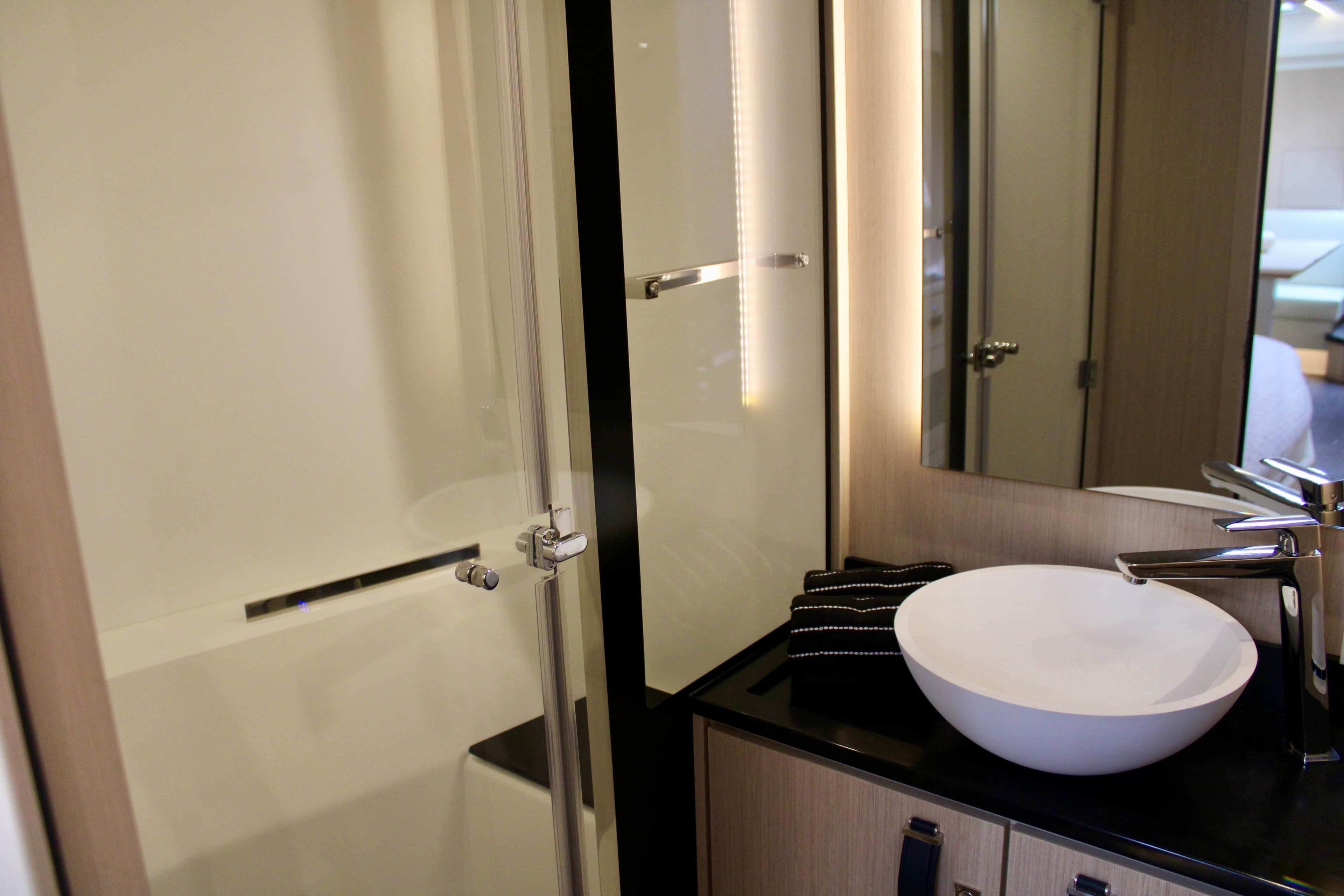 Modern bathroom in 2024 Jeanneau 55 yacht with vessel sink and glass shower.