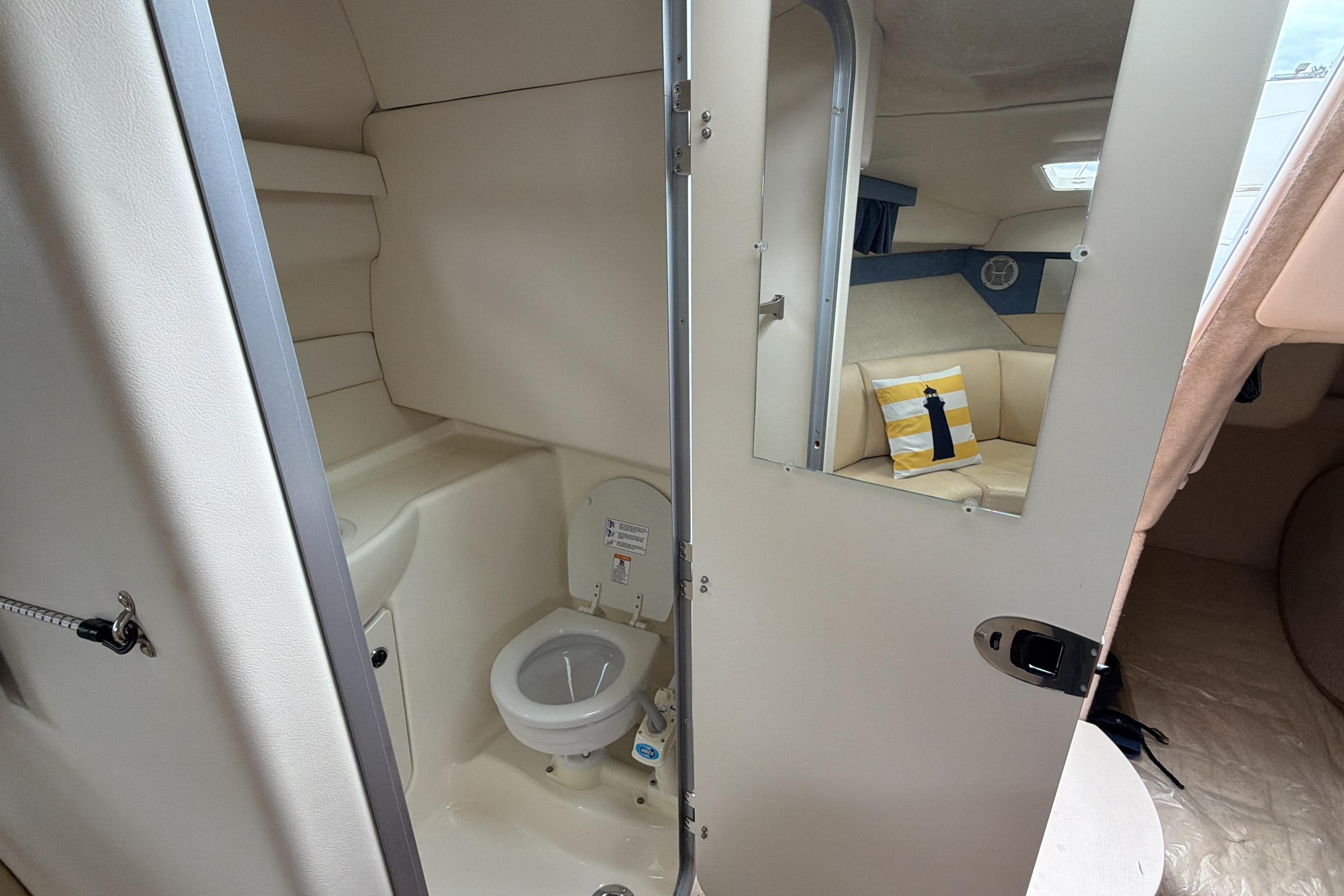 Interior of 2007 Bayliner 245 boat featuring compact bathroom and cozy seating area.