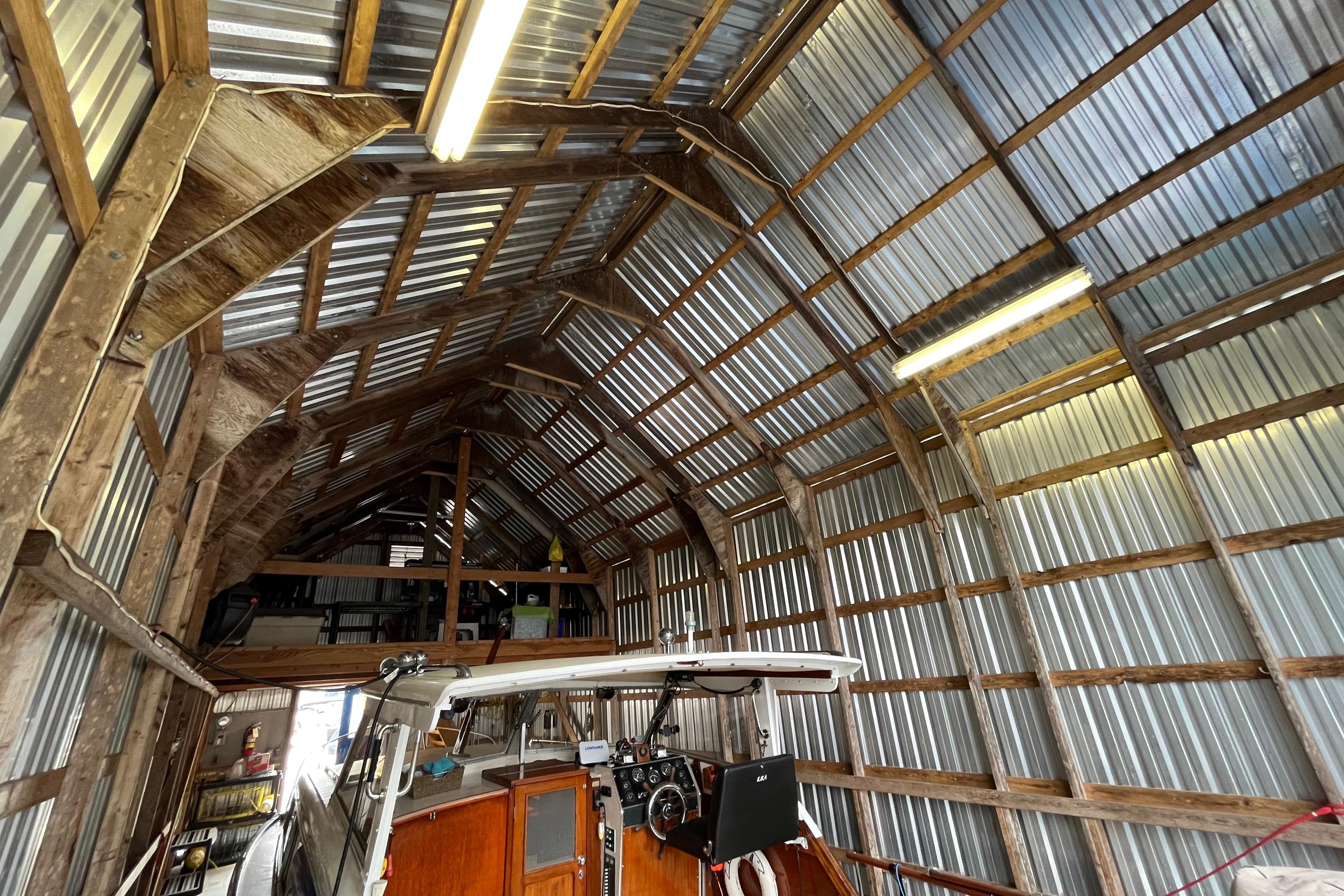 Interior of a custom boathouse with a 2020 model boat, featuring wooden and metal construction.